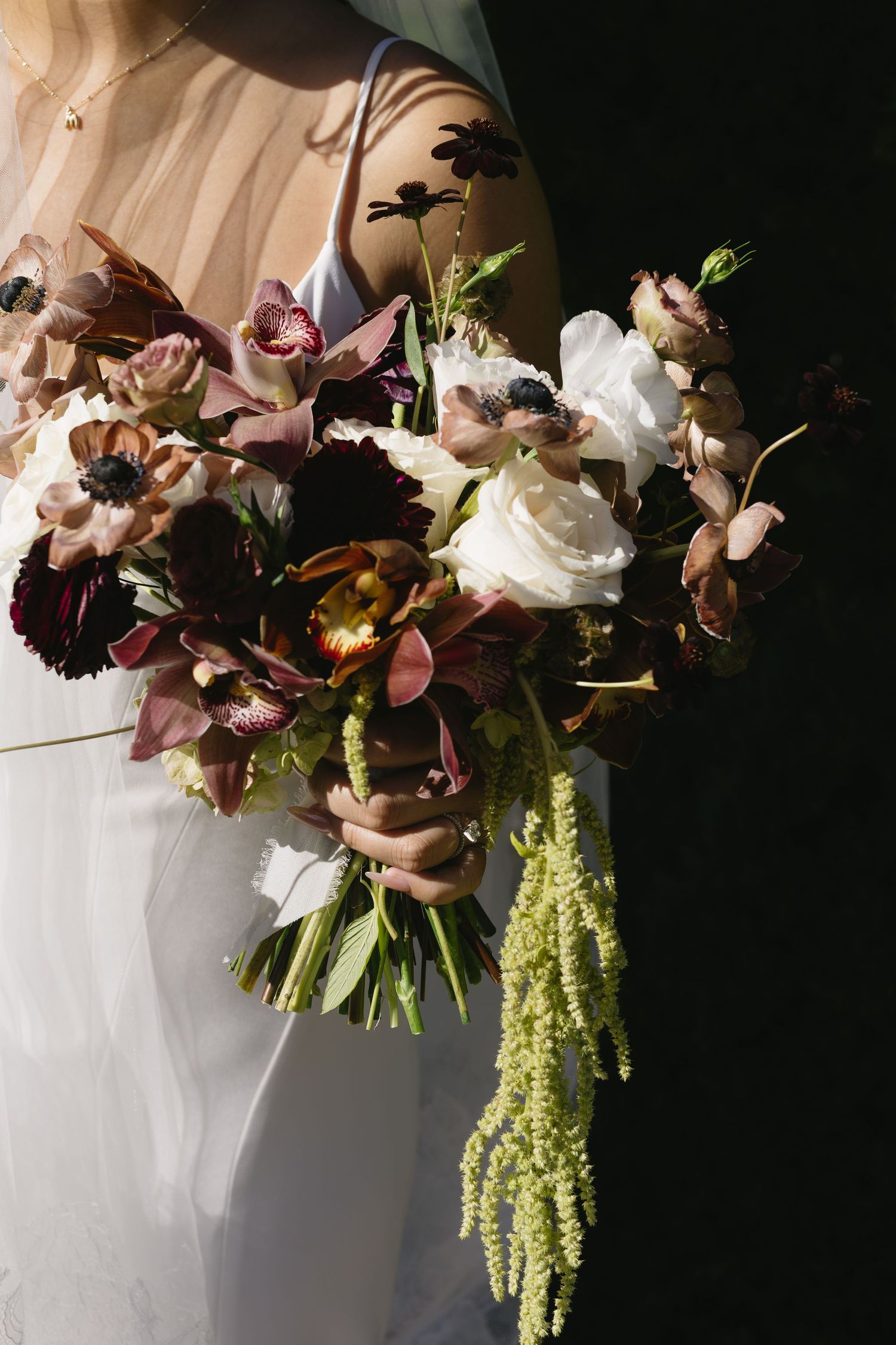 Artistic detail shot of a wedding bouquet with mauve roses and cascading greenery.