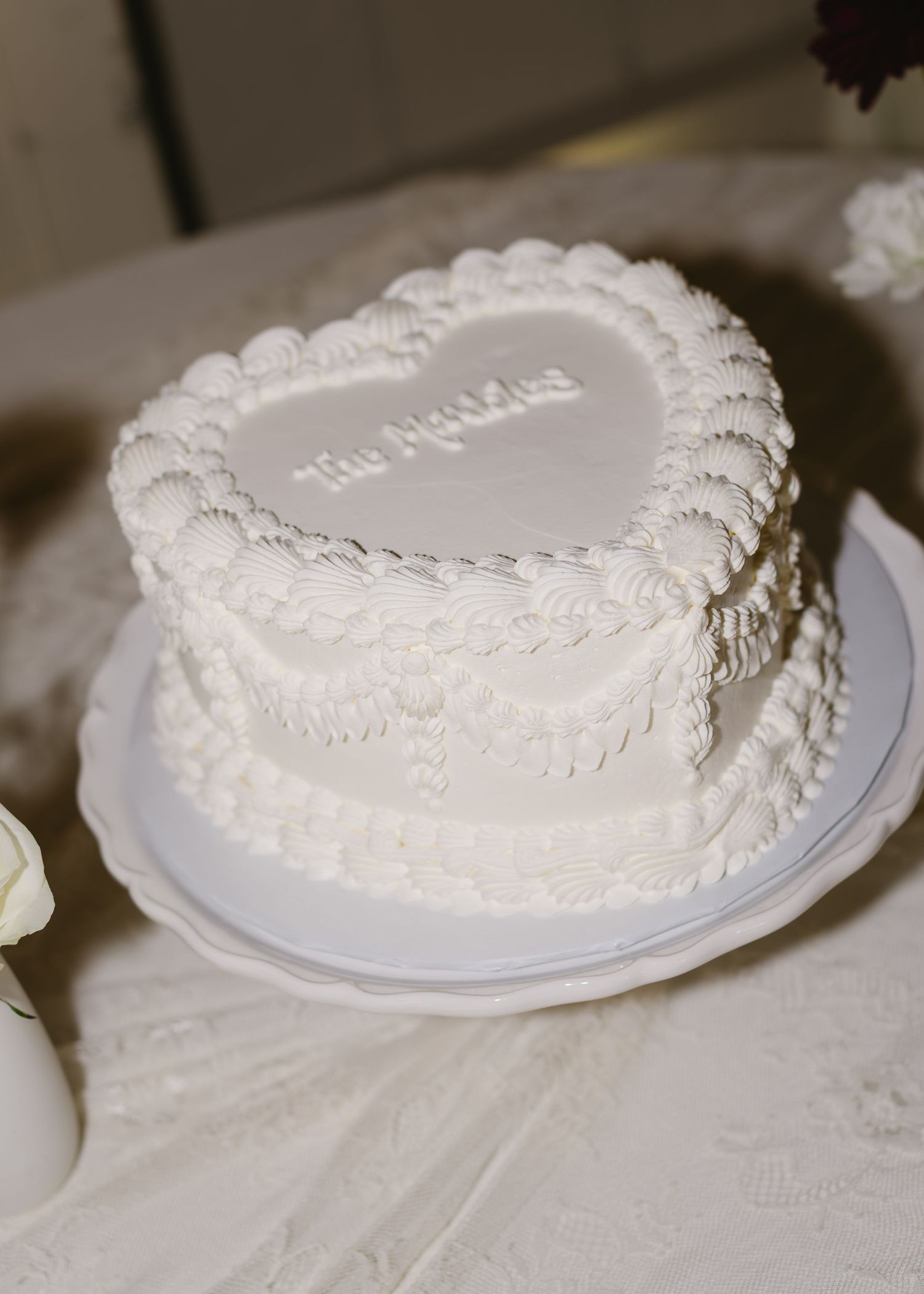 White wedding cake with delicate piped frosting details on display.