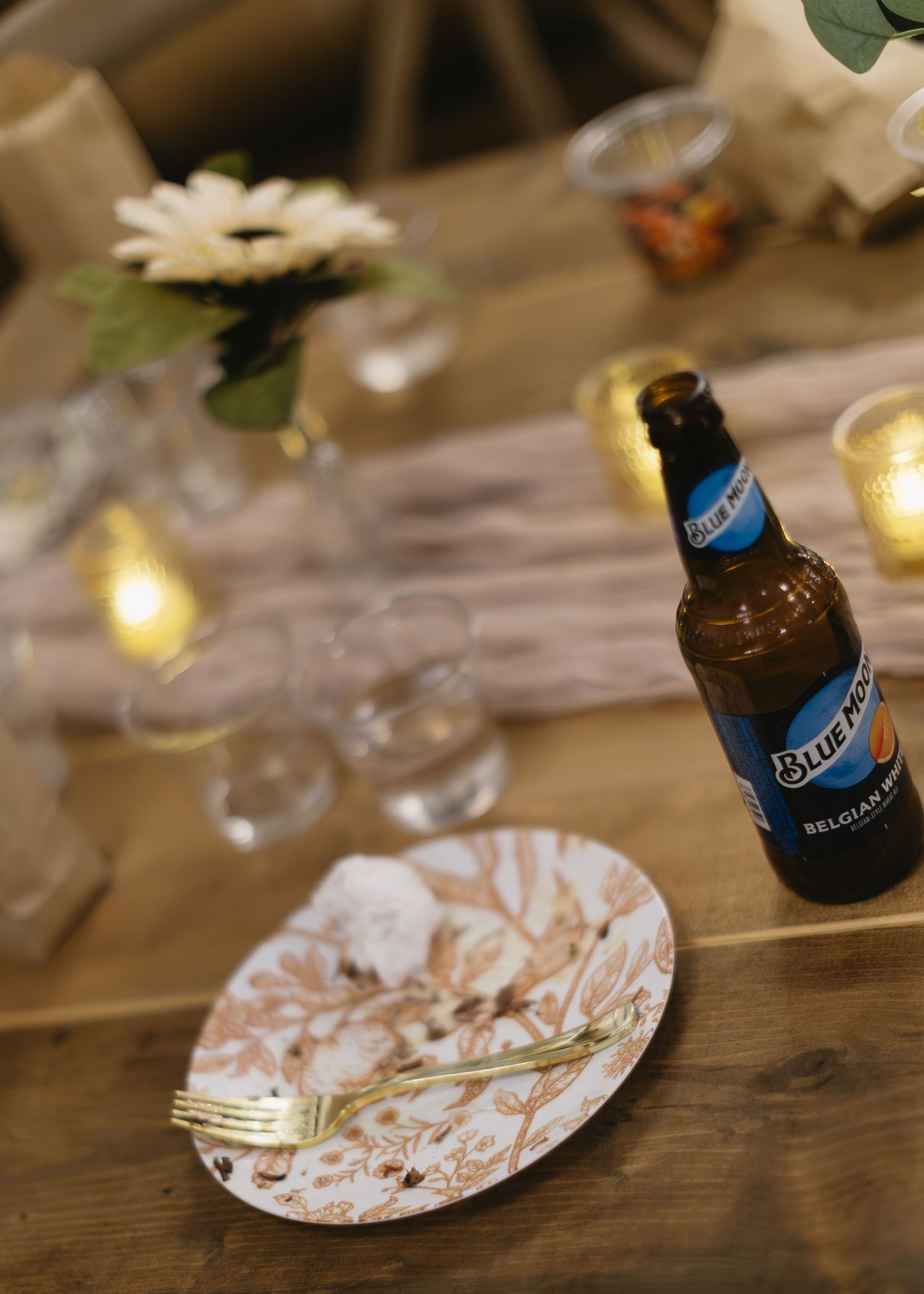 Decorative paper plates with floral designs and blue bottles on a wooden table setting.