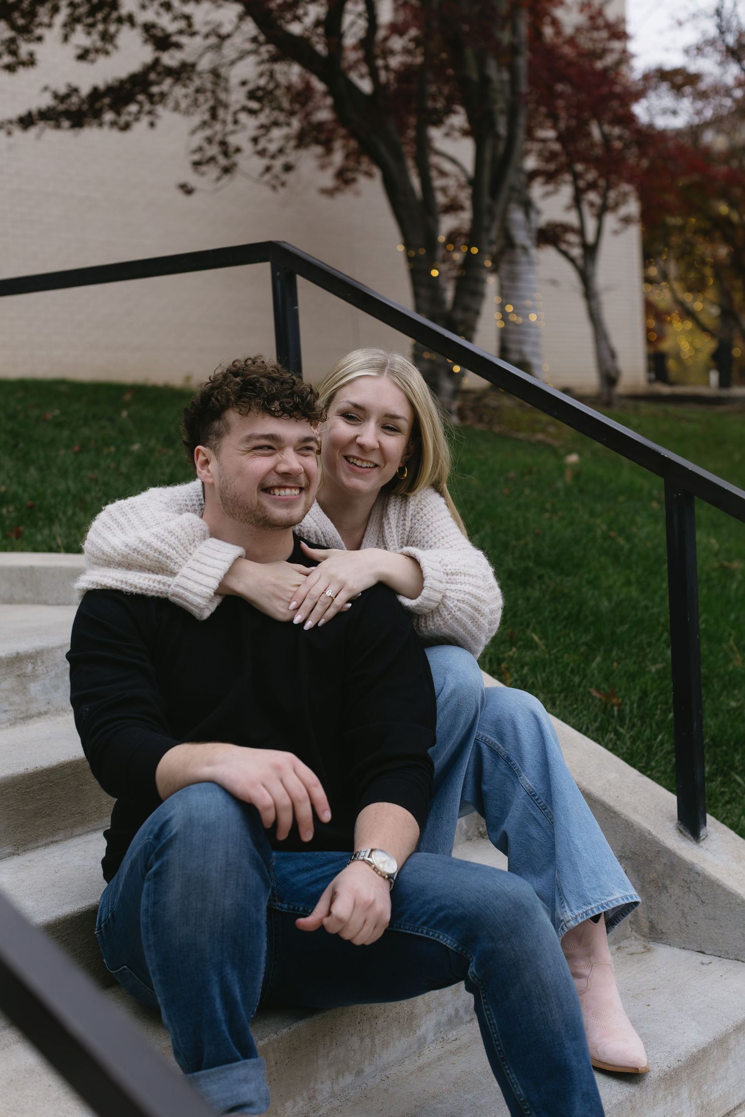 A couple sharing a tender moment while sitting on concrete steps outdoors.