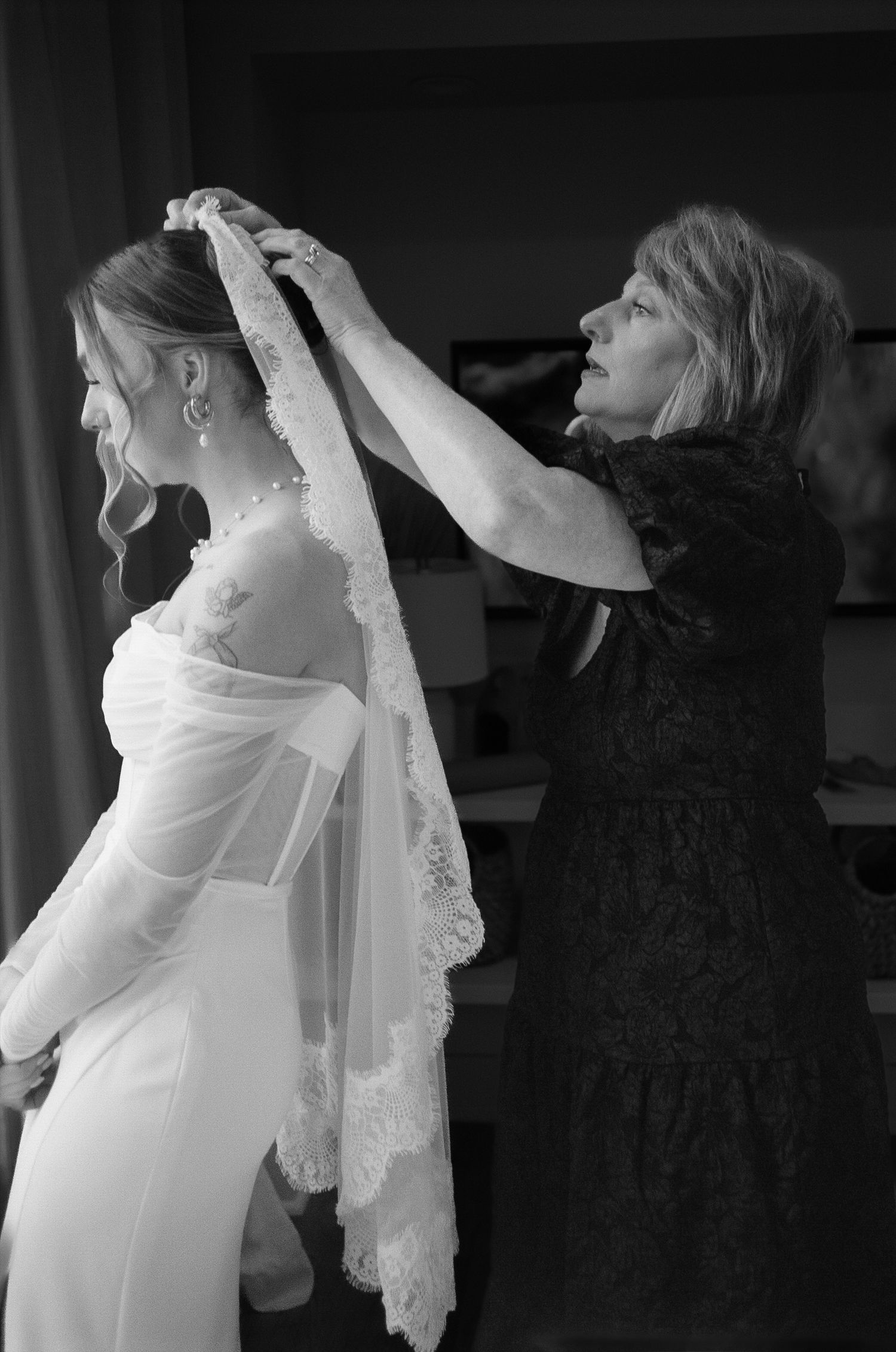 Black and white image of a wedding veil being adjusted in dramatic side lighting.