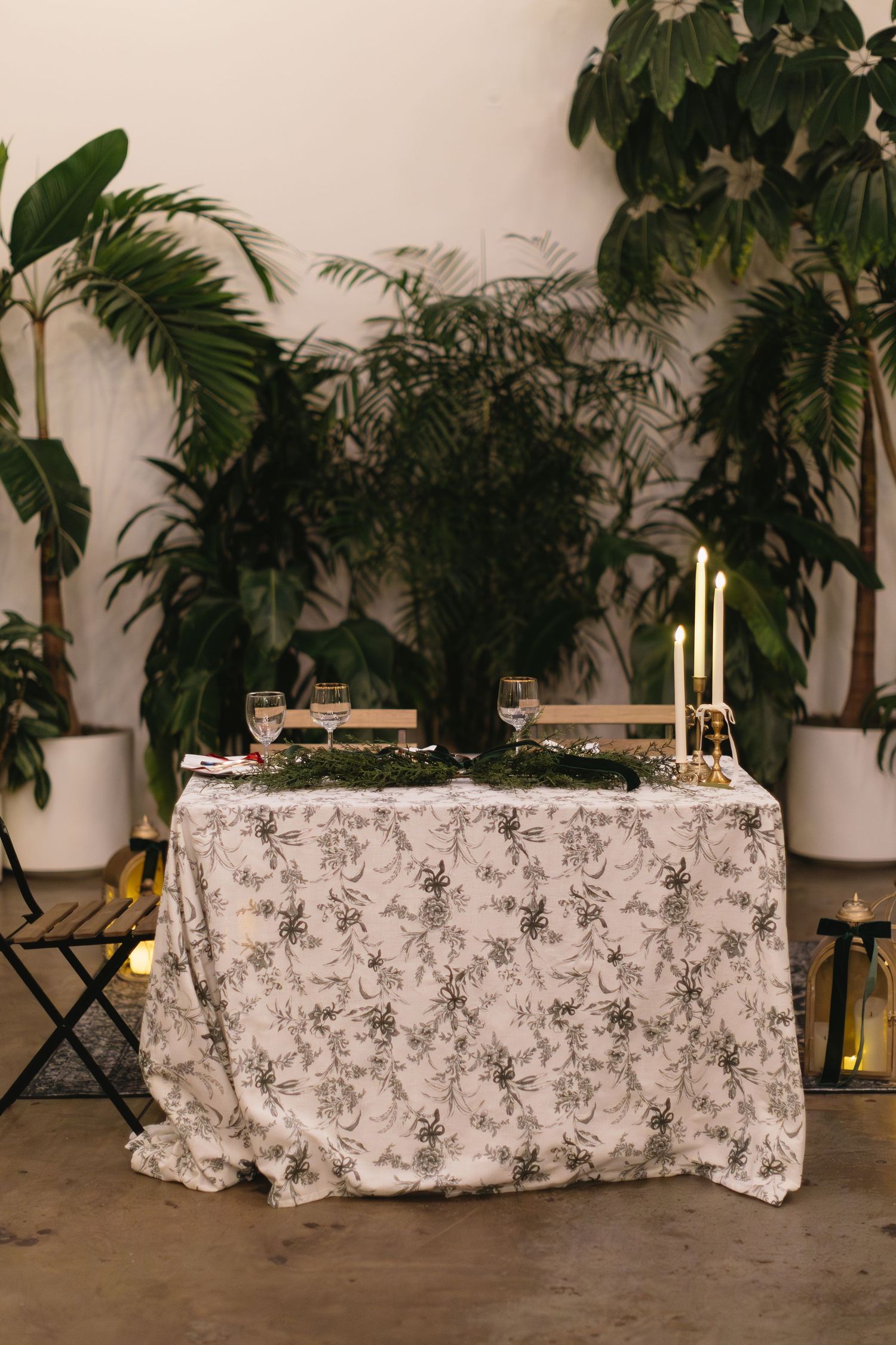 Reception tables with floral print tablecloths and tropical plants in background.