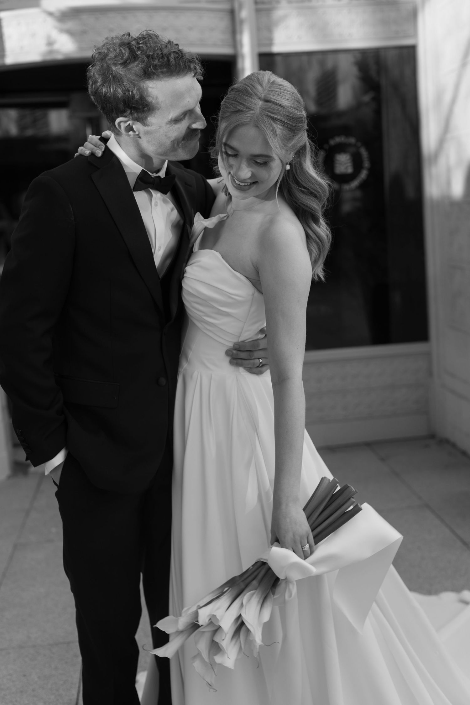 A couple shares an intimate moment in black and white as they embrace during their wedding celebration.