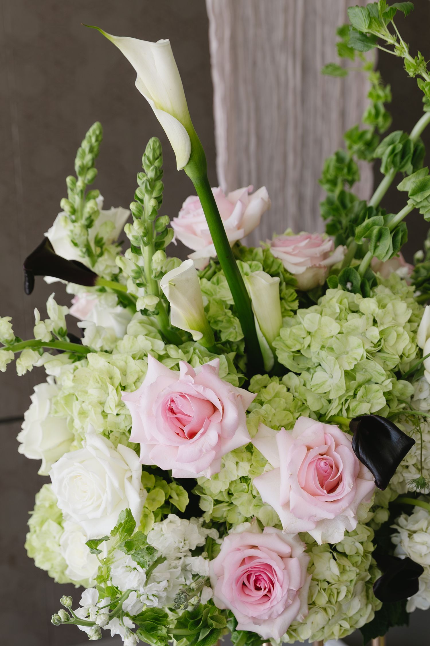 Elegant floral arrangement with pink roses and white hydrangeas against gray backdrop.