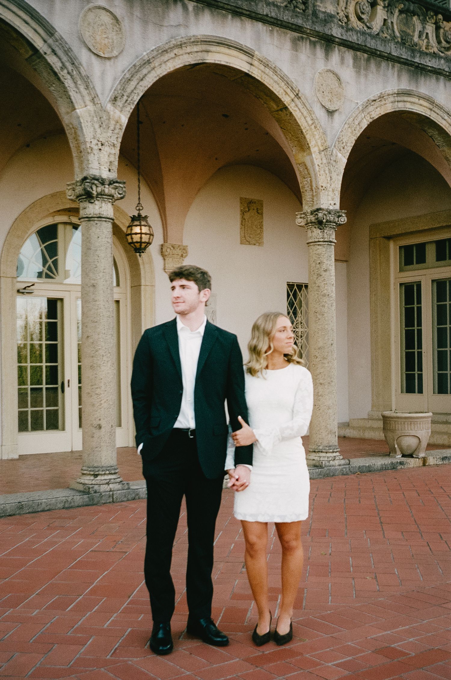 A couple laughs together under a beautiful arched colonnade.