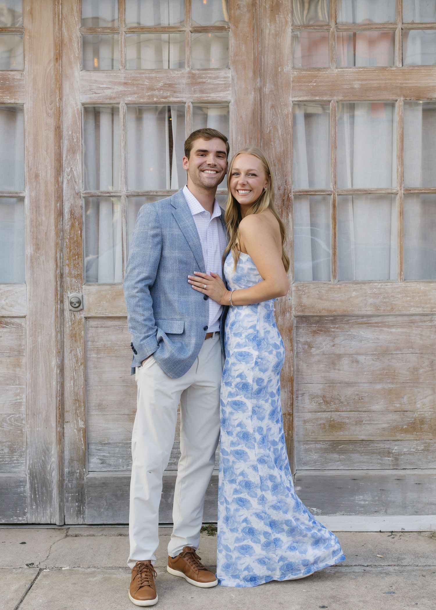 A couple poses together against a rustic wooden wall during a photo session.
