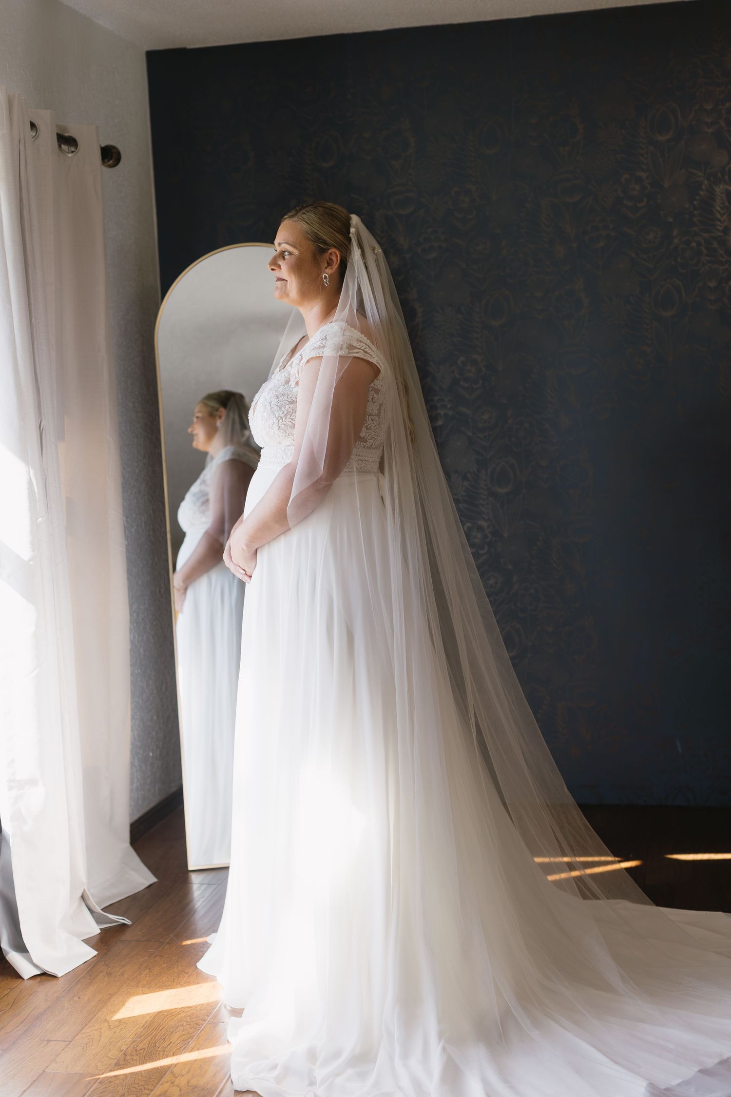 Elegant bridal portraits in a room with dramatic lighting and flowing white wedding dress.