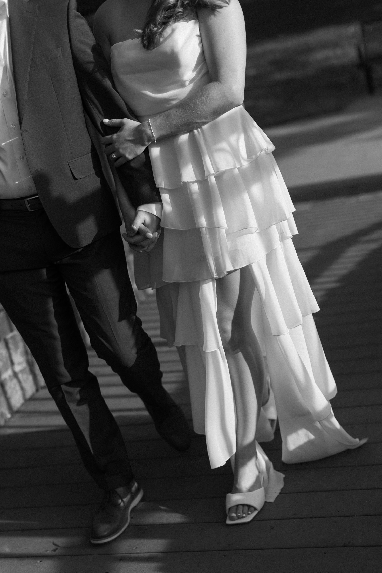 Black and white photo showing couple's feet during wedding dance, with bride's layered white dress flowing.