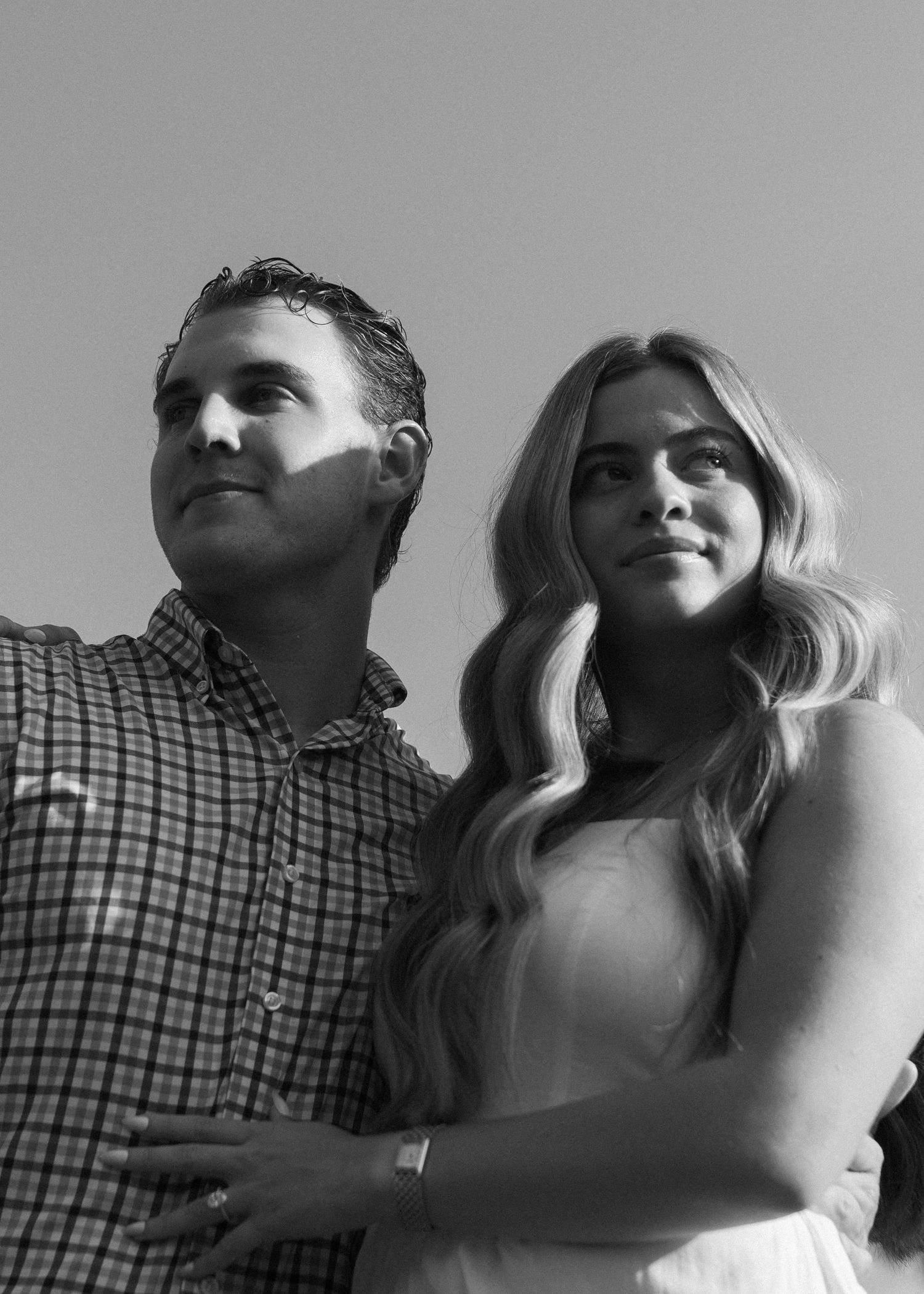 A black and white portrait of a couple looking up against a plain background.
