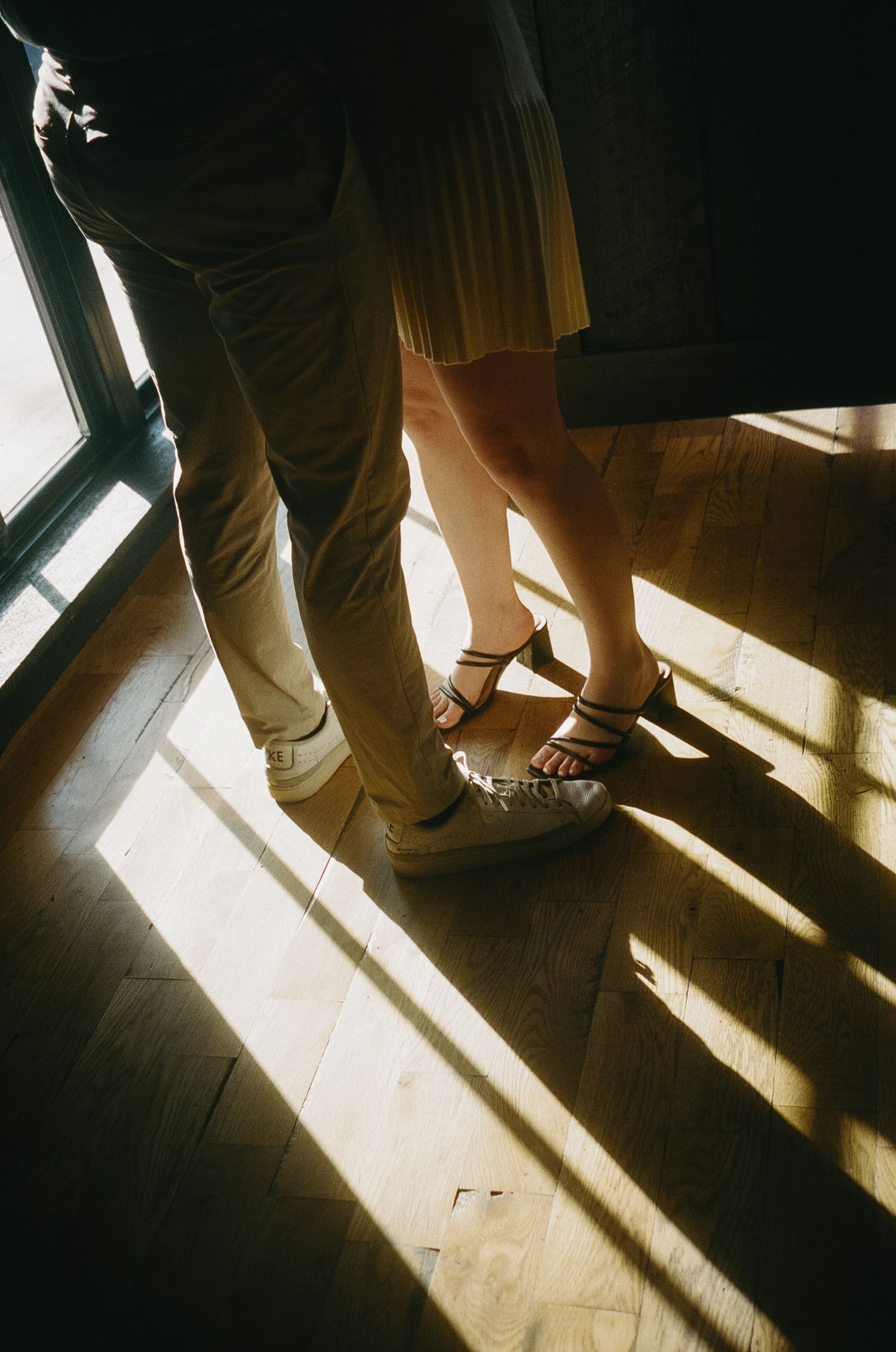 Dramatic shadows cast by sunlight through window panes create geometric patterns on hardwood floor.