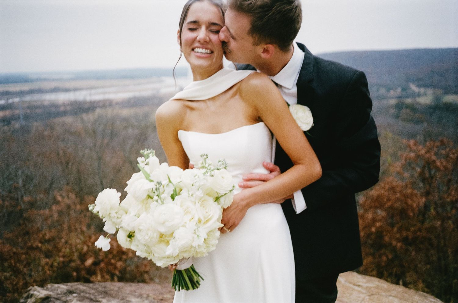 Newlyweds share intimate moments against a scenic autumn mountain backdrop.