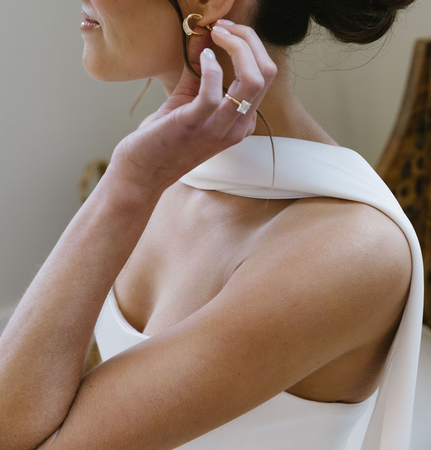 Close-up view of a bride in a sleeveless white wedding dress holding a wooden sign.
