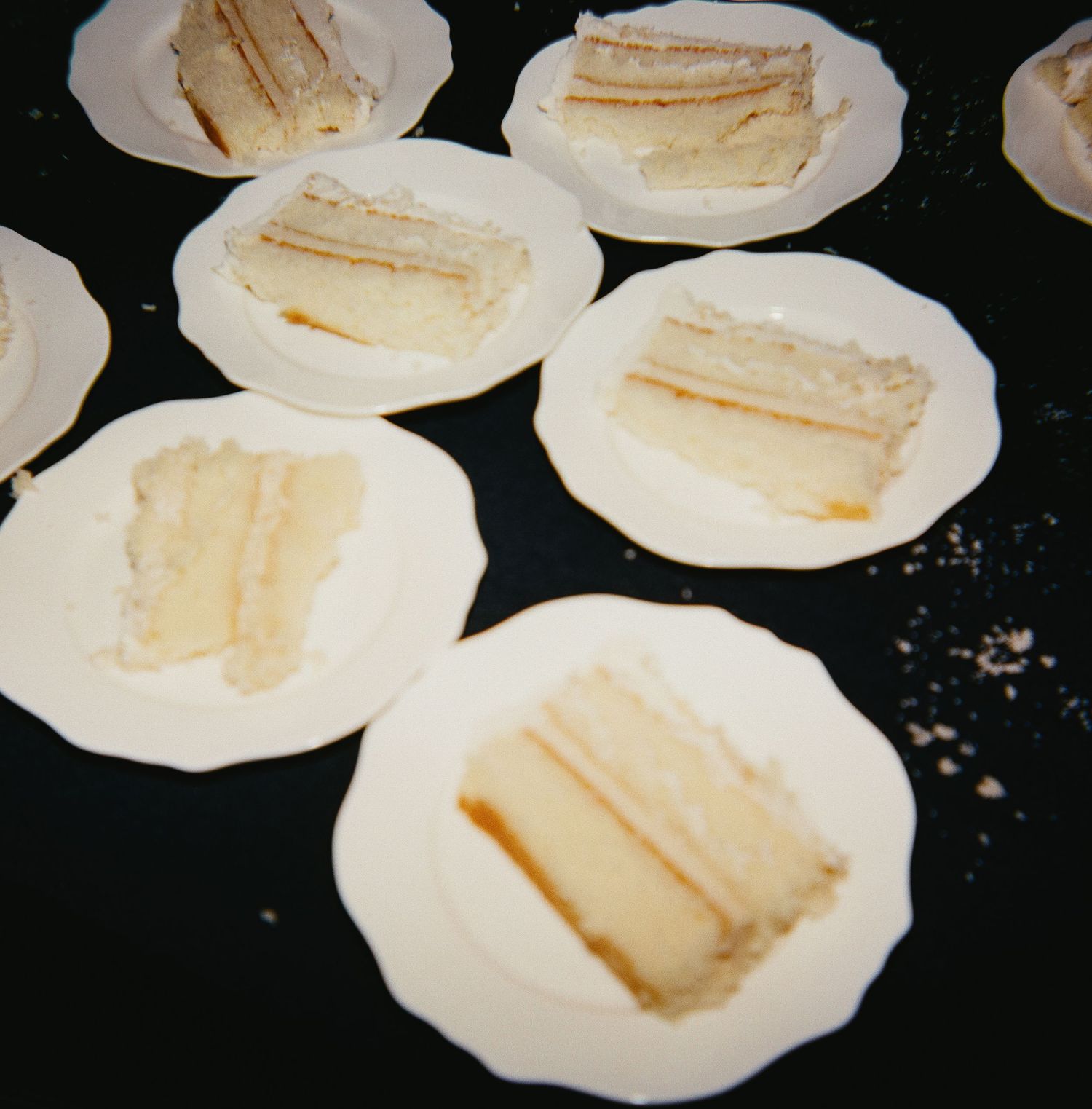White plates arranged in a row displaying sandwich portions on a dark surface.