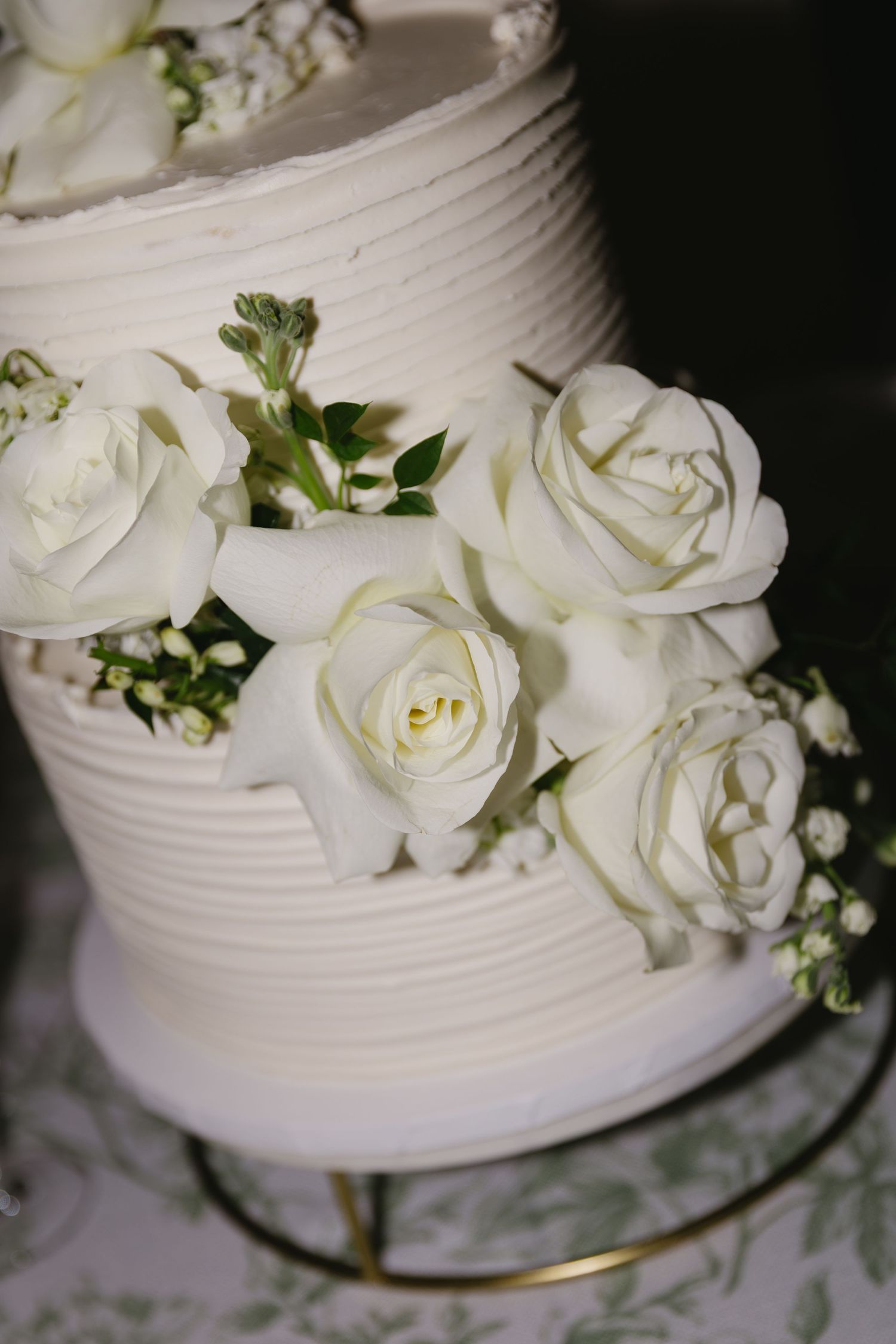 White wedding cake decorated with fresh roses and delicate piped details.