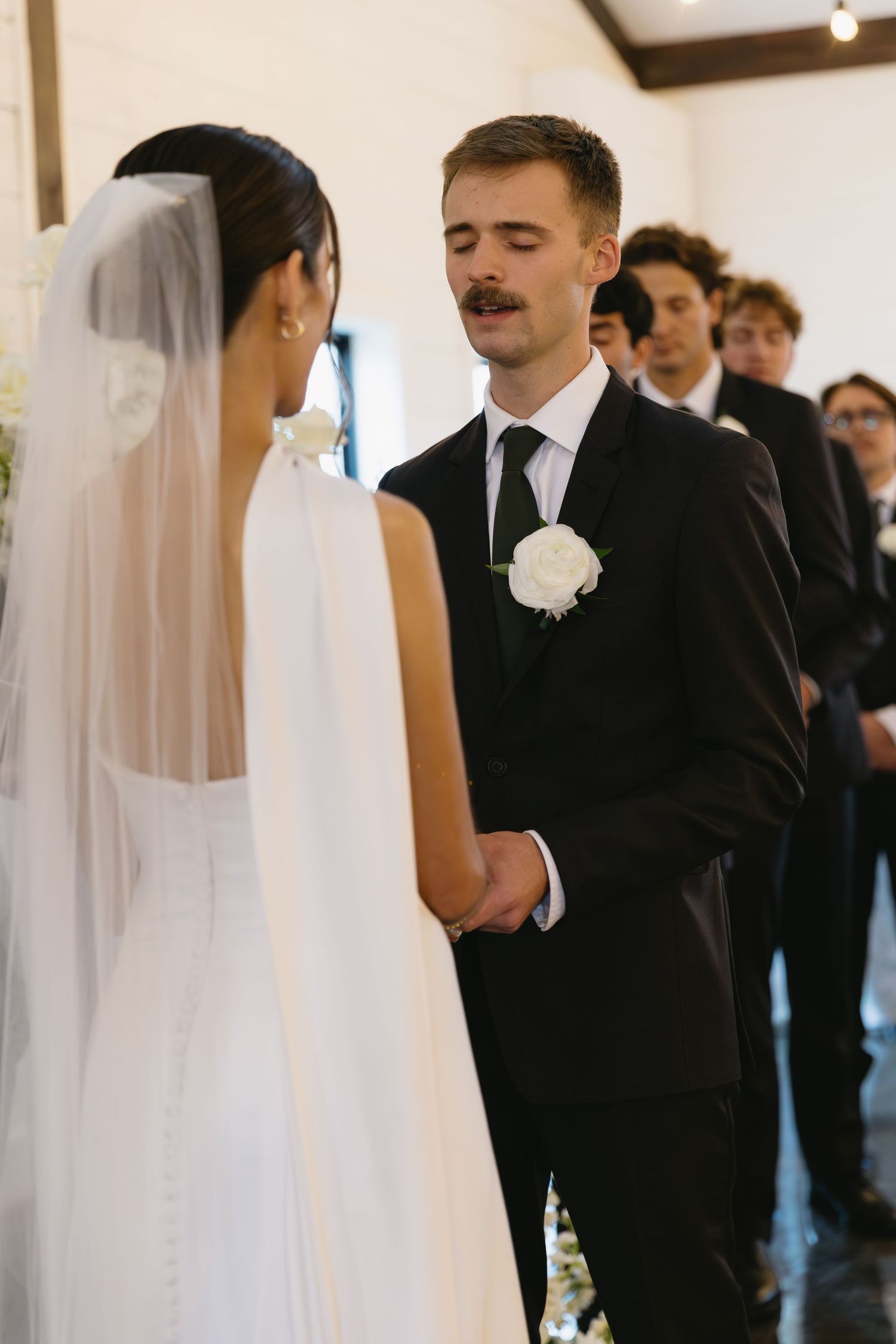 Elegant wedding ceremony scene with formal attire and flowing white veil.