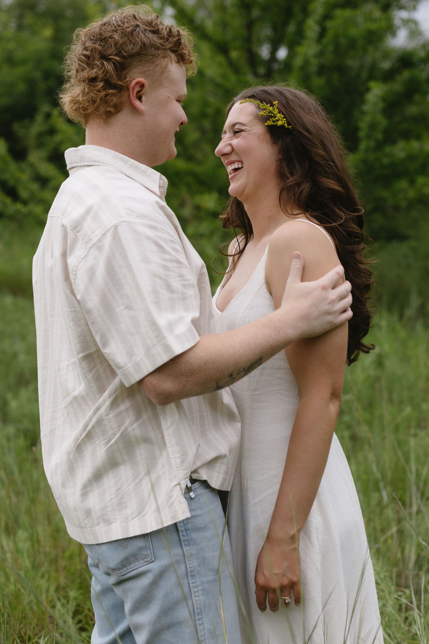 Two people share intimate moments while laughing together in an outdoor setting.