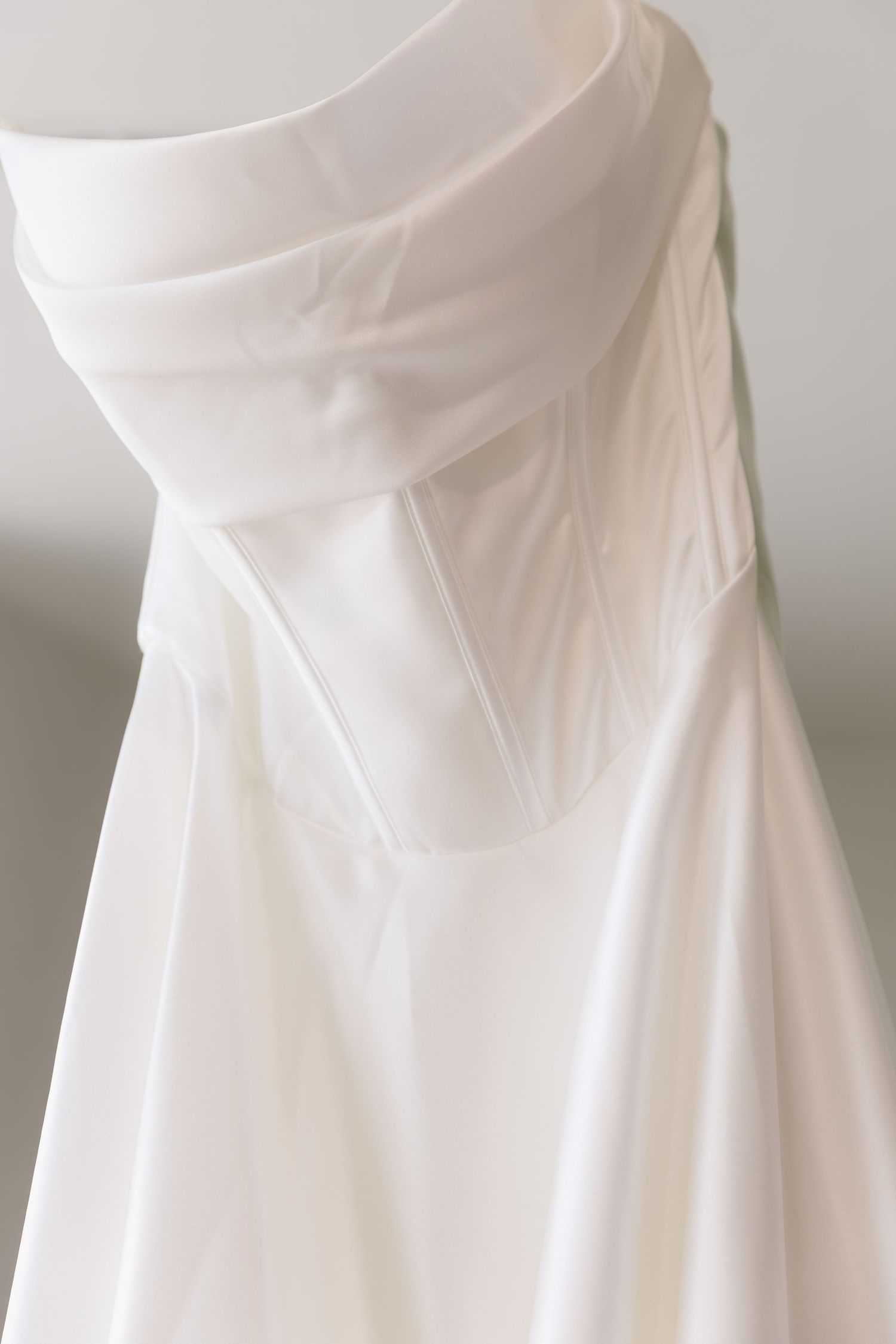 Close-up details of pleated white wedding dress fabric showing intricate draping and texture.
