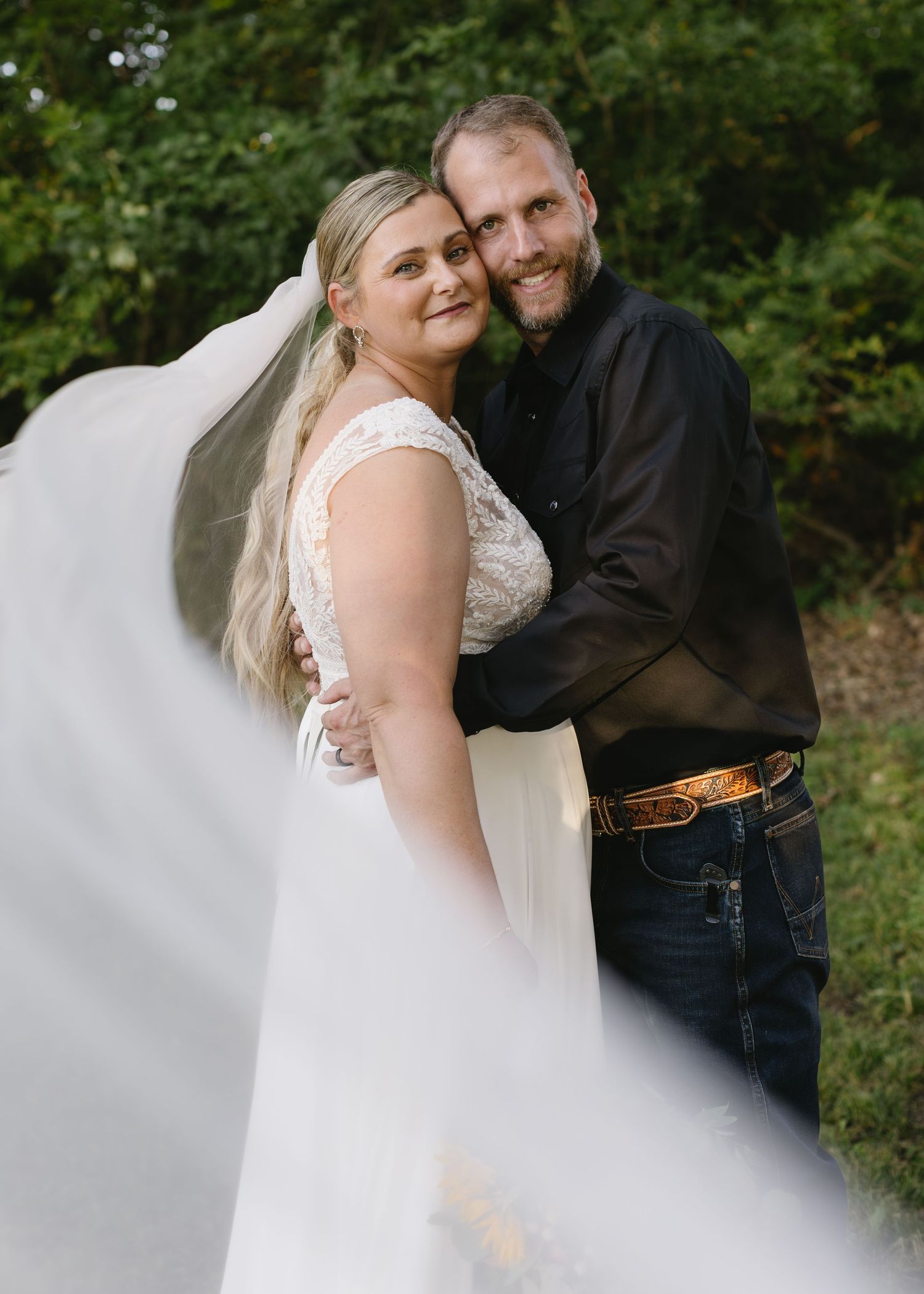 A romantic wedding photoshoot in a garden setting with flowing white dress details.