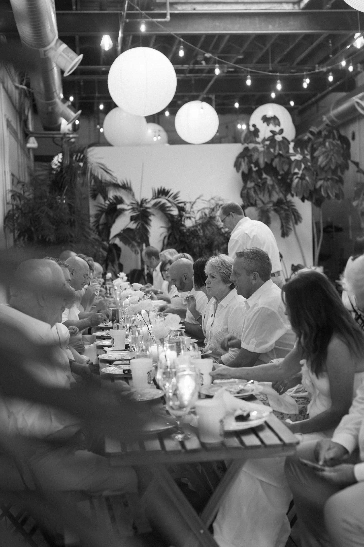 A festive indoor dining setup with string lights, paper lanterns, and tropical plants.