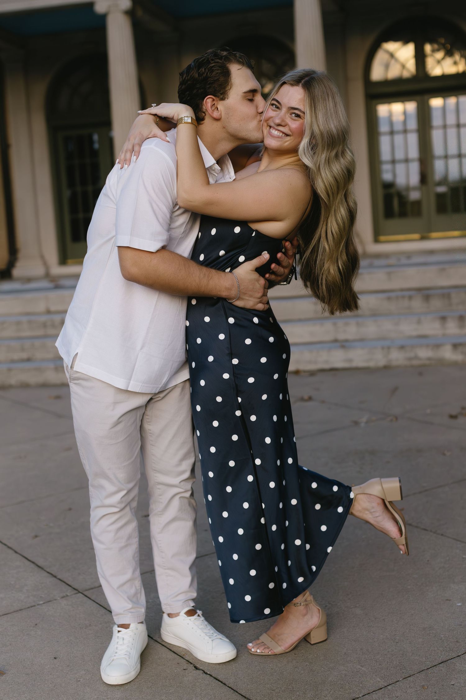 Close-up shots of a couple embracing, with polka dot dress and white attire contrasting against stone steps.