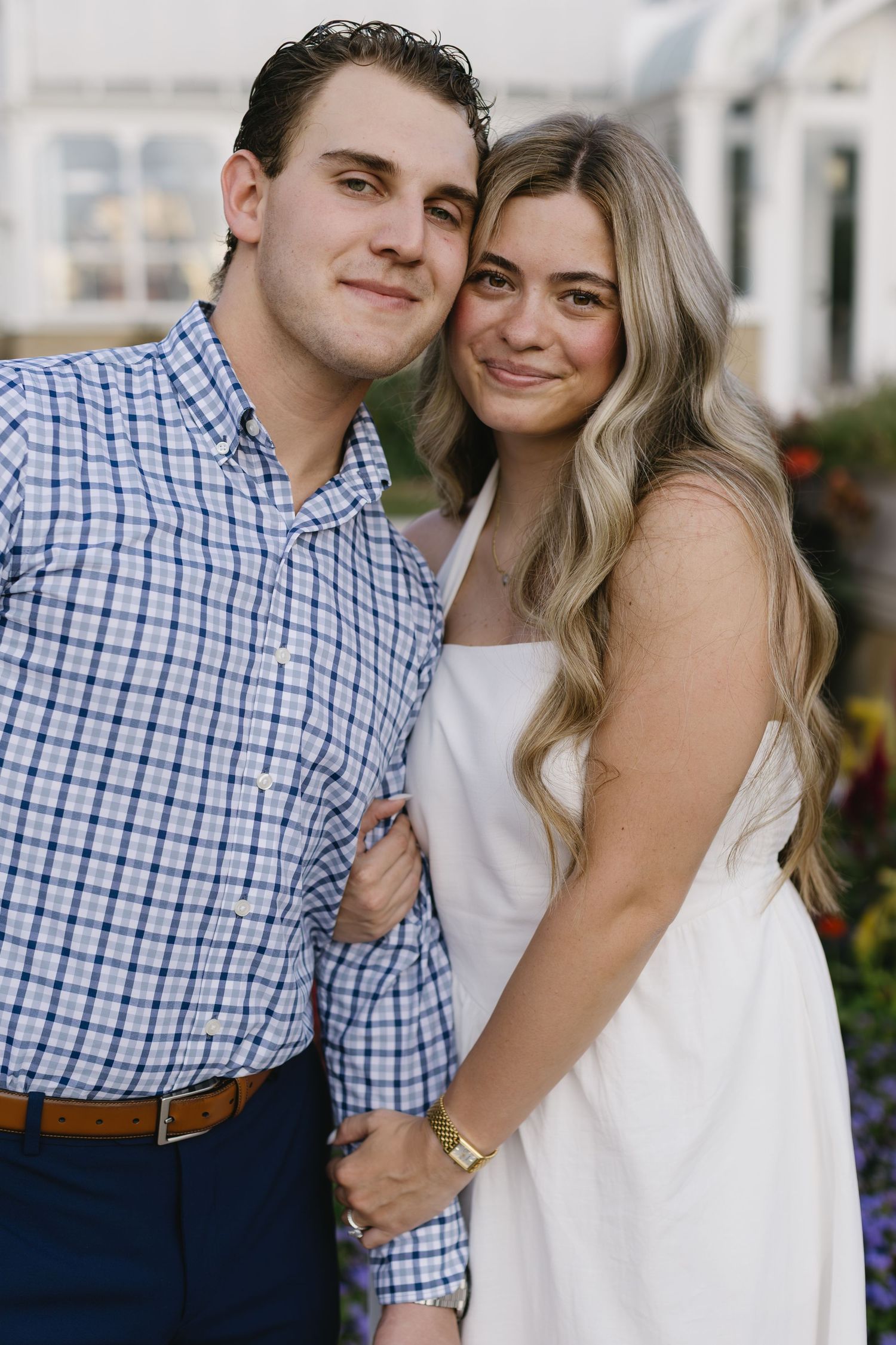 Happy couple poses closely together outdoors in coordinated blue and white outfits.