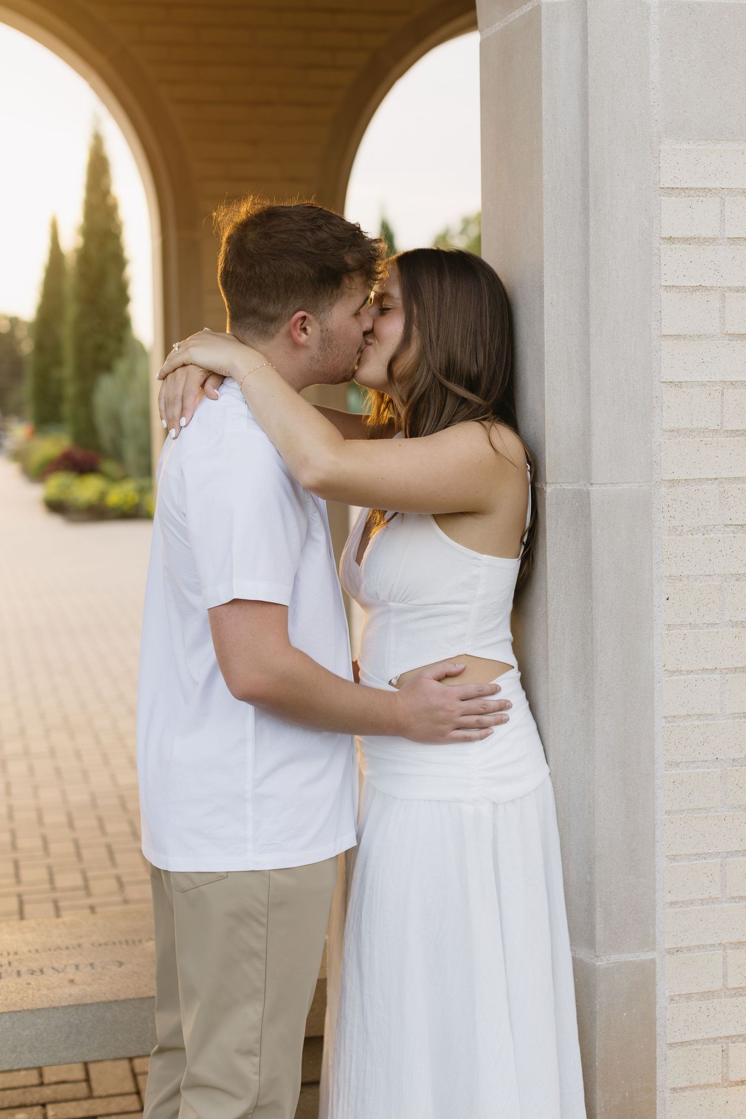 A romantic moment beneath white arched columns and brick architecture.