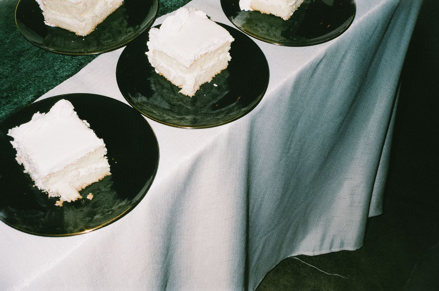Overhead view of white wedding cake slices served on dark plates.