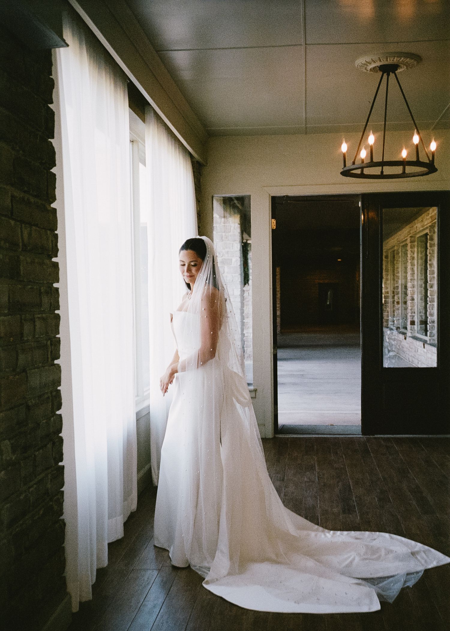 Long hallway with natural light streaming through windows, featuring flowing white fabric.
