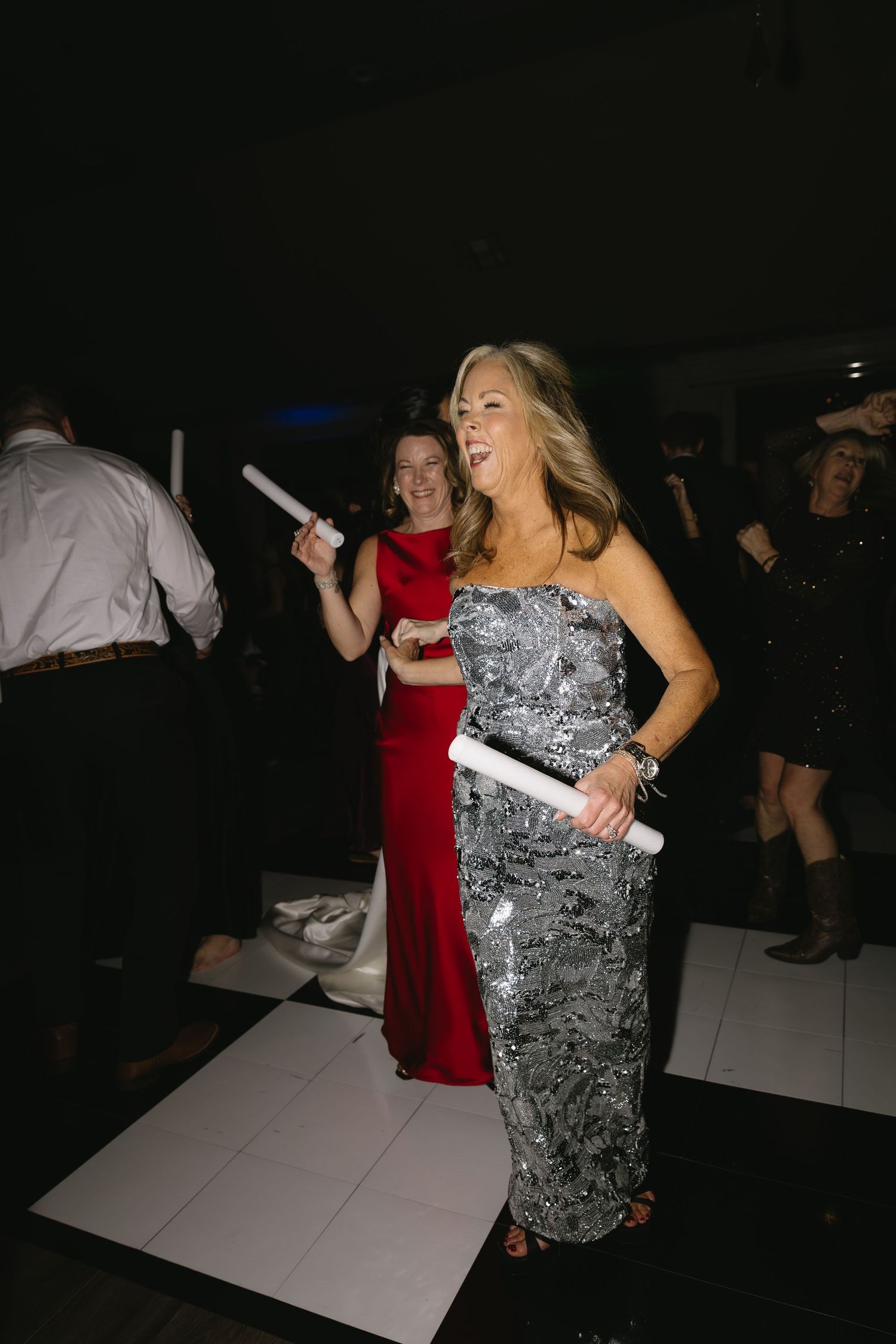 Guests dancing at an elegant reception wearing formal evening gowns.