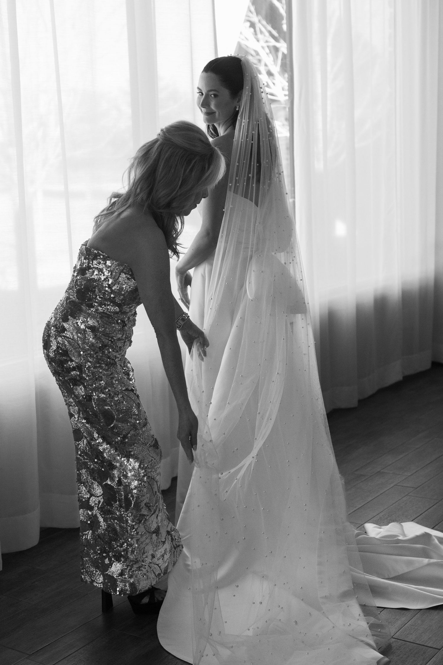 A touching moment of dress preparation with a flowing white wedding veil.
