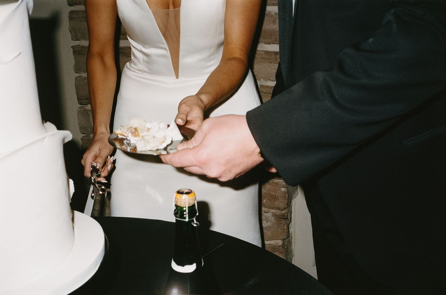 Close-up details of formal attire and hands during wedding reception.