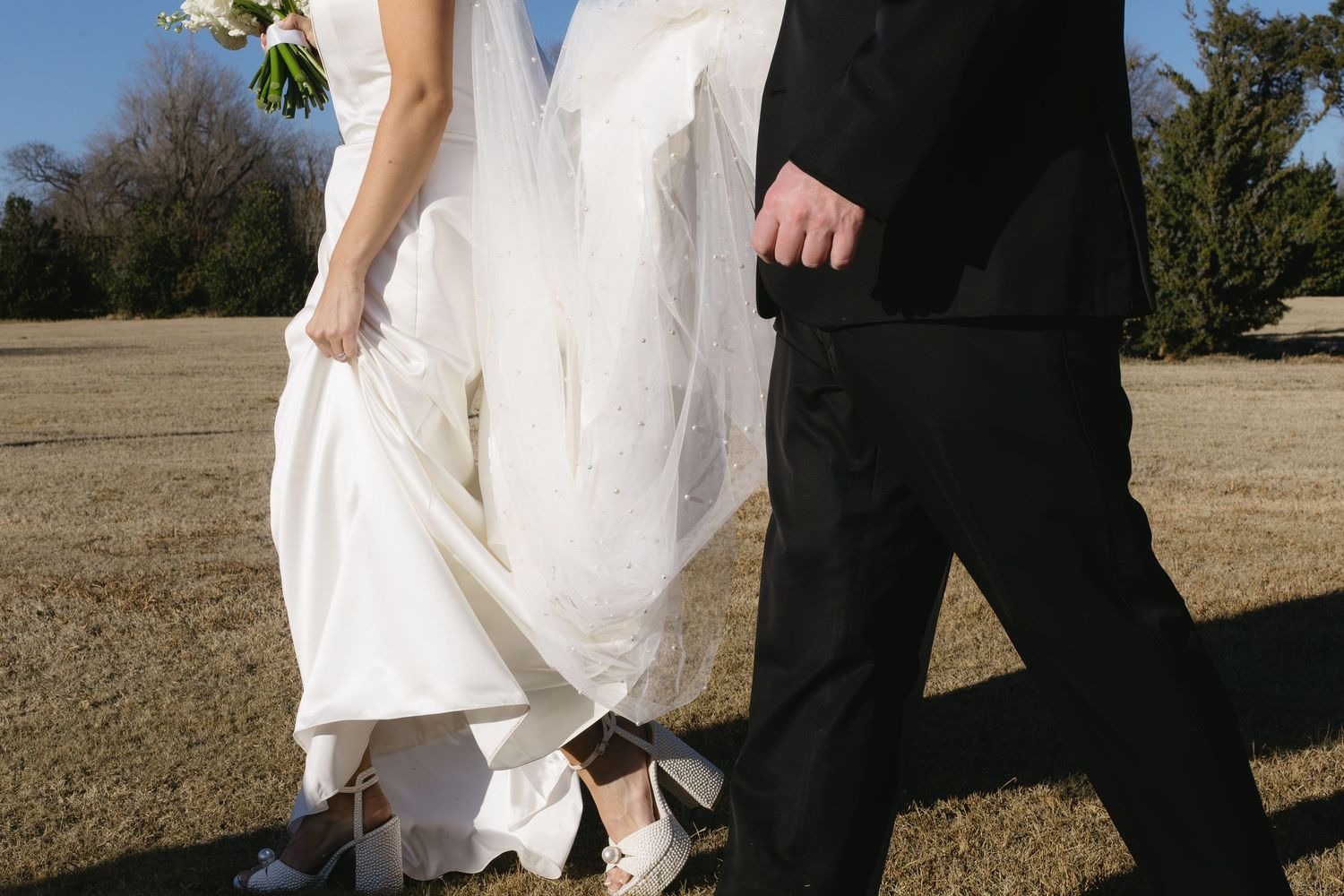 Wedding couple walking through a sunny outdoor venue.