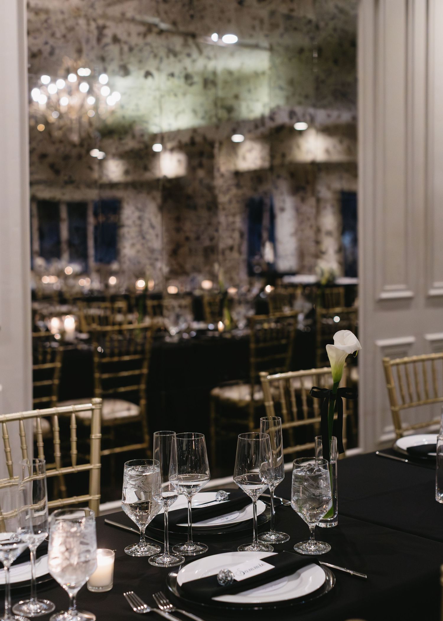 Elegant wedding reception venue with gold chairs and crystal chandeliers set for formal dining.