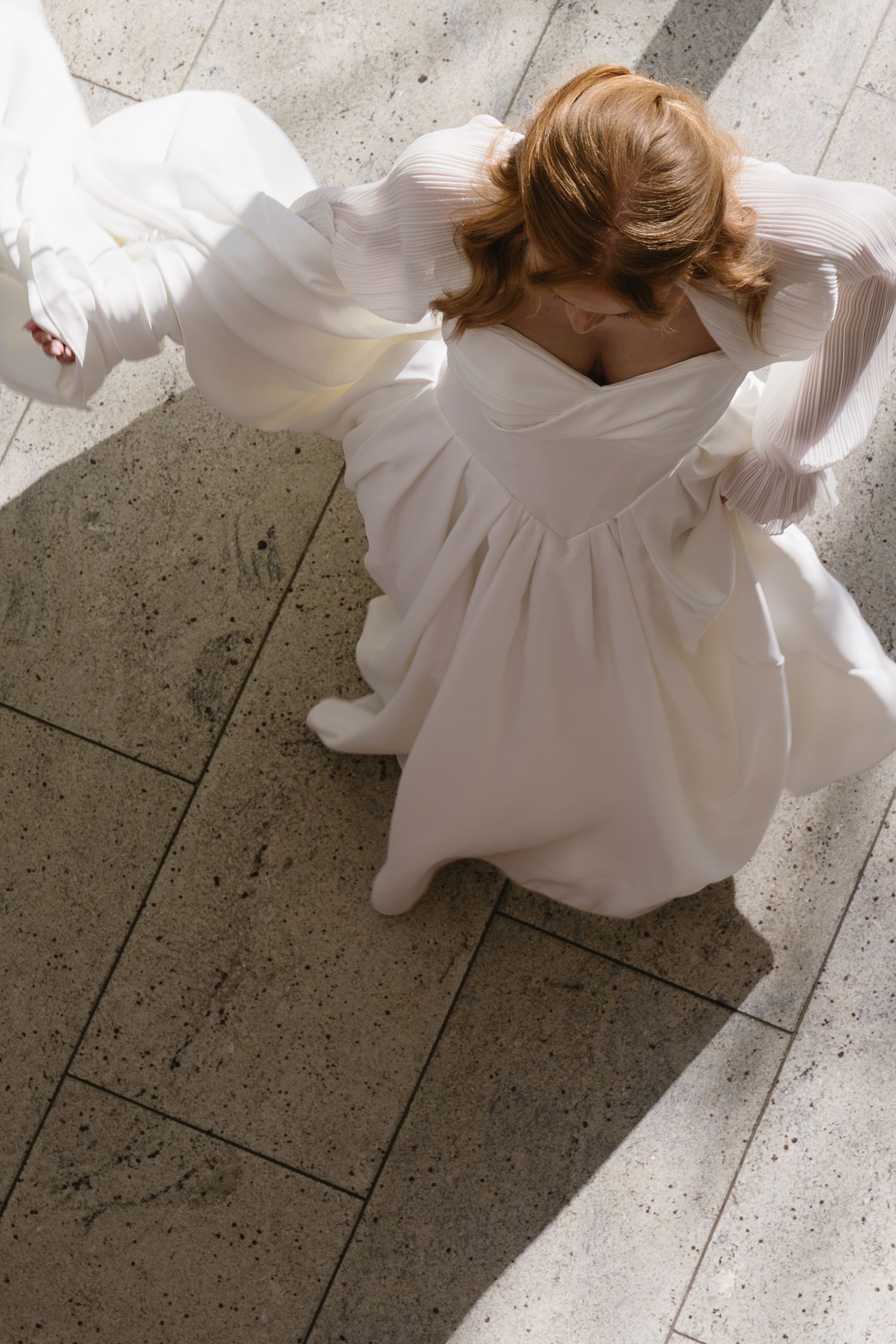 Artistic overhead shots of a white wedding dress flowing across stone flooring.