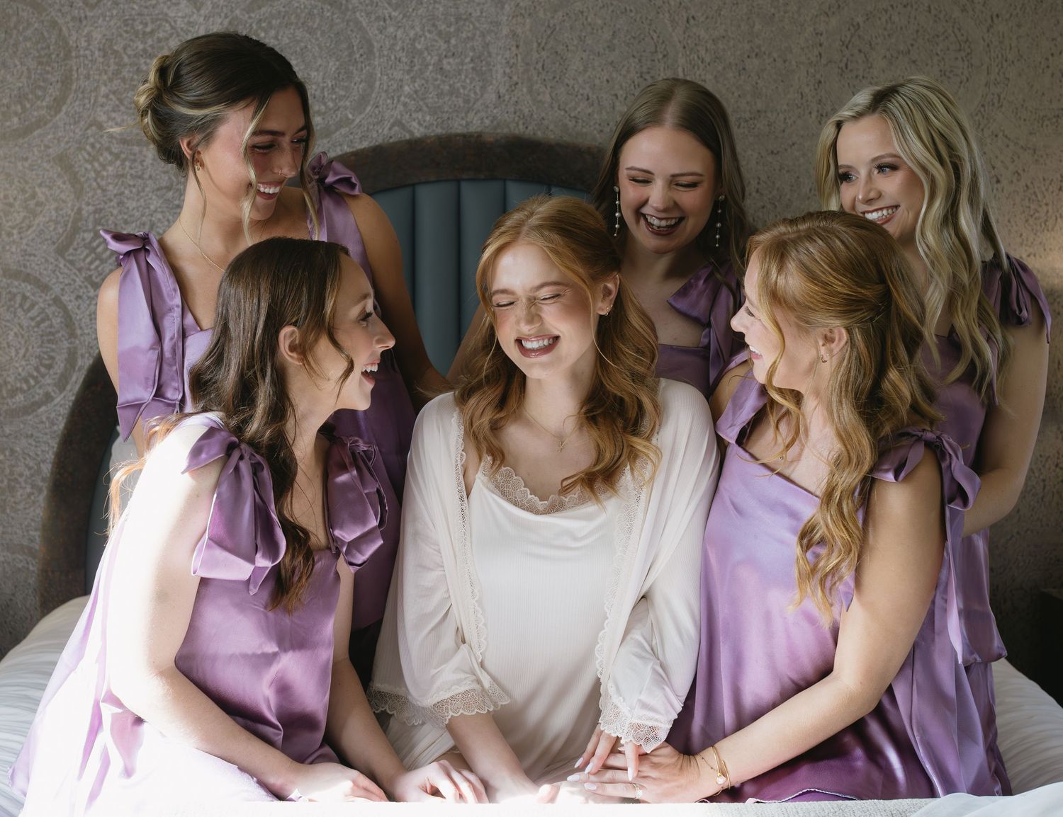 A group wearing lavender dresses gather together in a joyful moment.