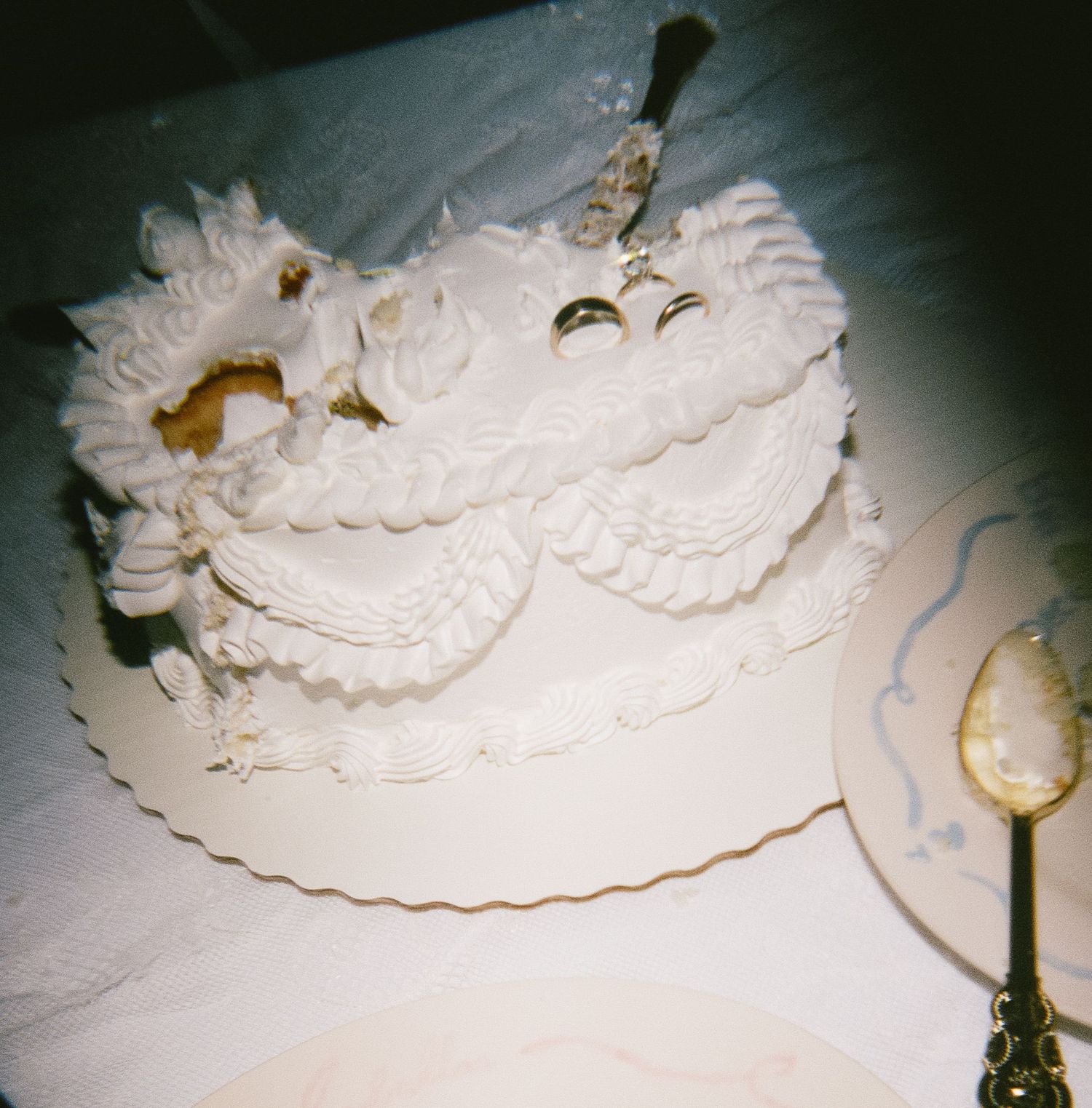 A white wedding cake decorated with intricate piped frosting designs and ornate details sits elegantly on a table.