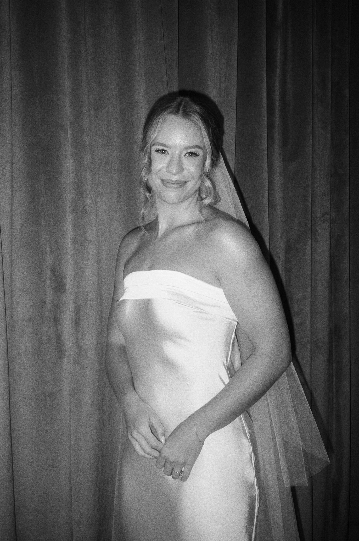 Black and white portrait of bride in classic strapless wedding dress with cathedral veil.