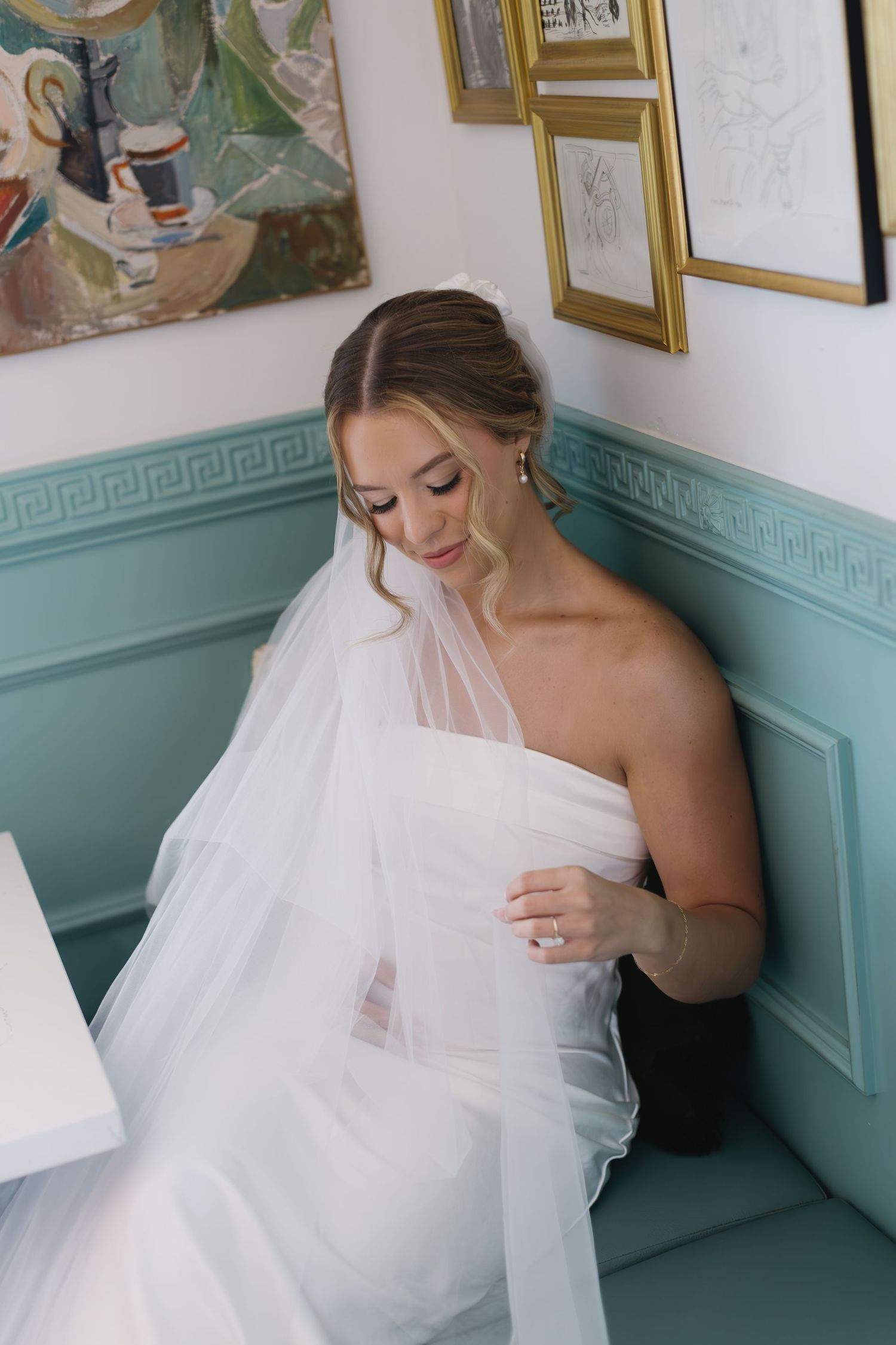 Candid bridal moments captured against turquoise walls with vintage framed artwork.