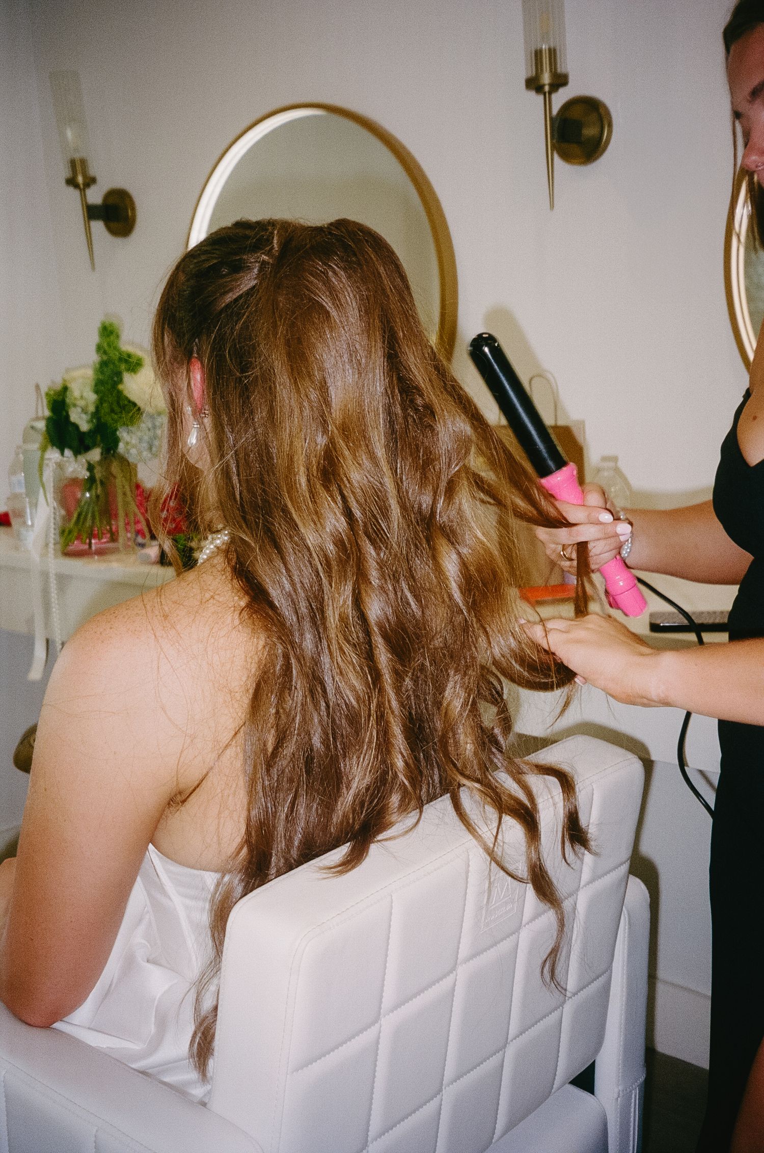 Behind the scenes of wedding preparation showing hair styling in progress.