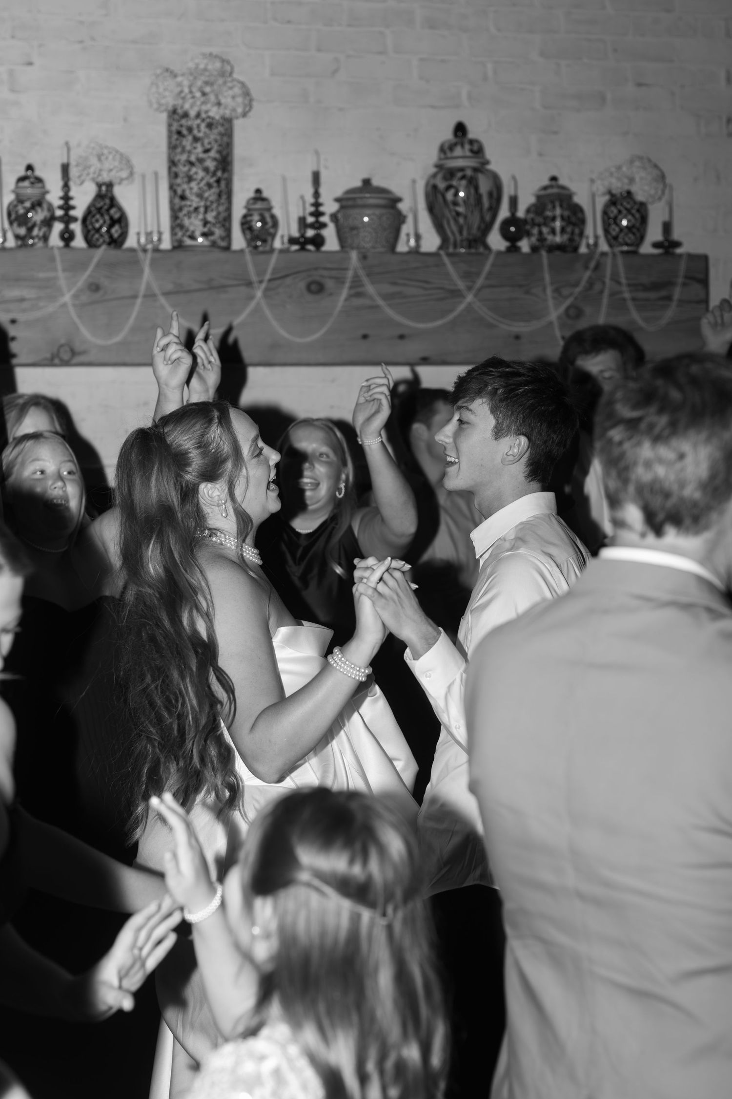 Black and white photograph of wedding guests dancing at a lively reception party.