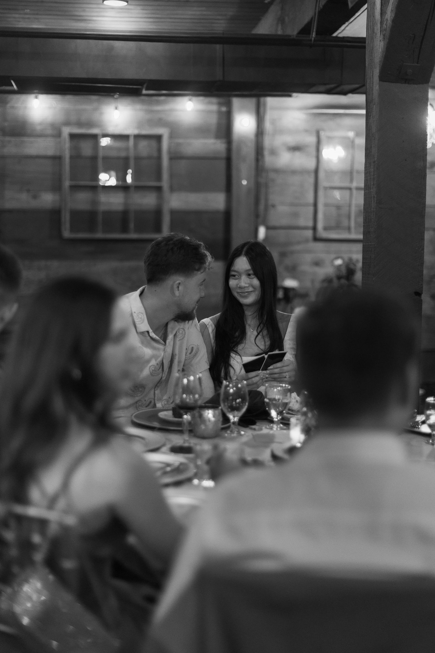 Guests enjoy dinner and conversation at a dimly lit indoor reception venue.