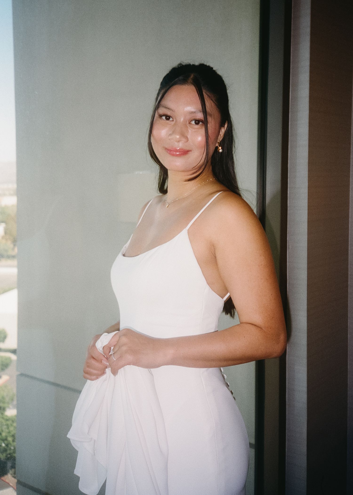 A white wedding dress being prepared in a sunlit room.