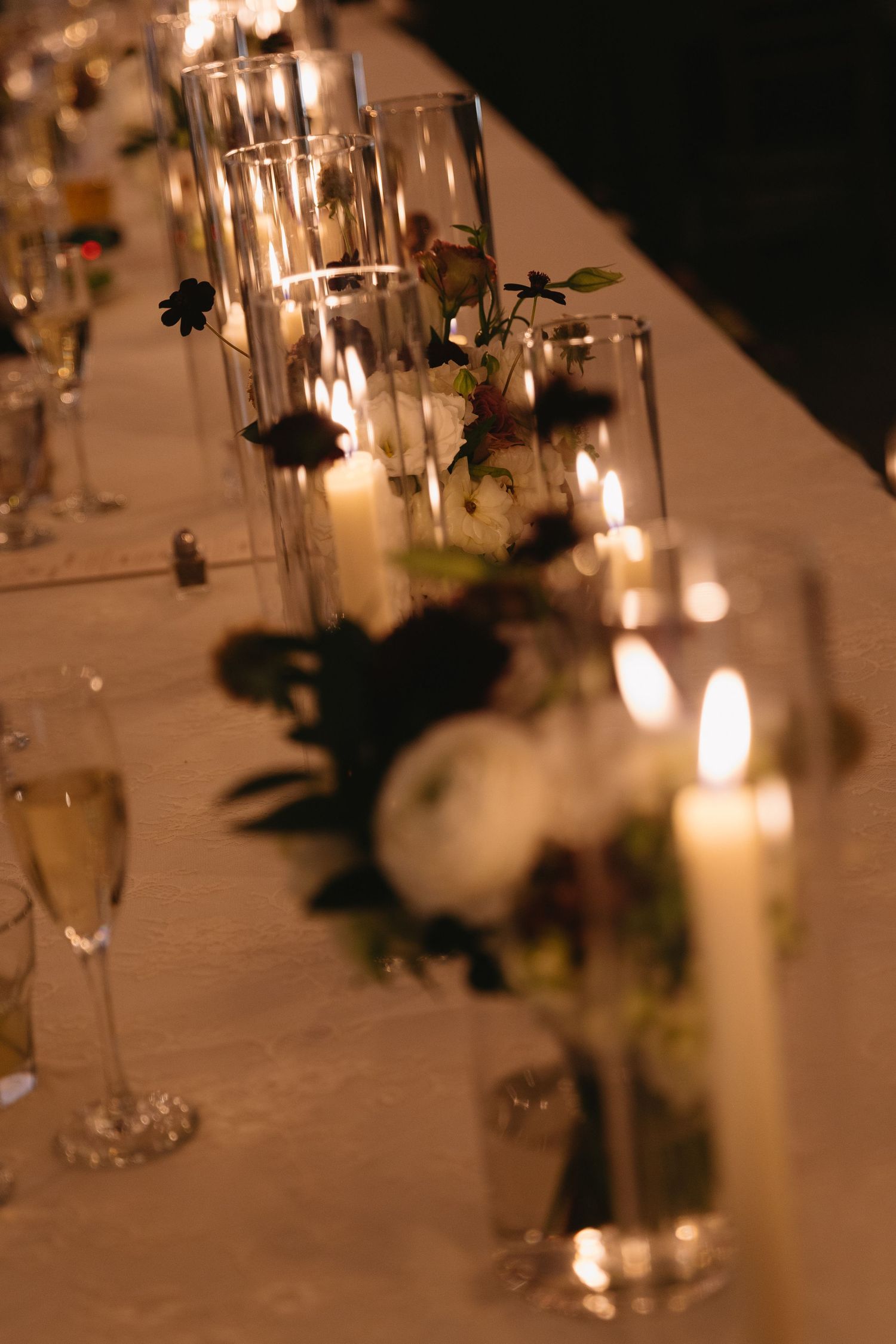 Romantic candlelit wedding reception table with elegant glassware and floral centerpieces.