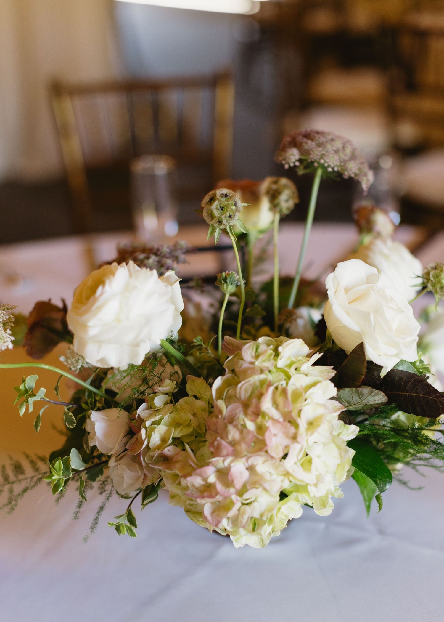 Elegant floral centerpiece with white roses and greenery on reception table.