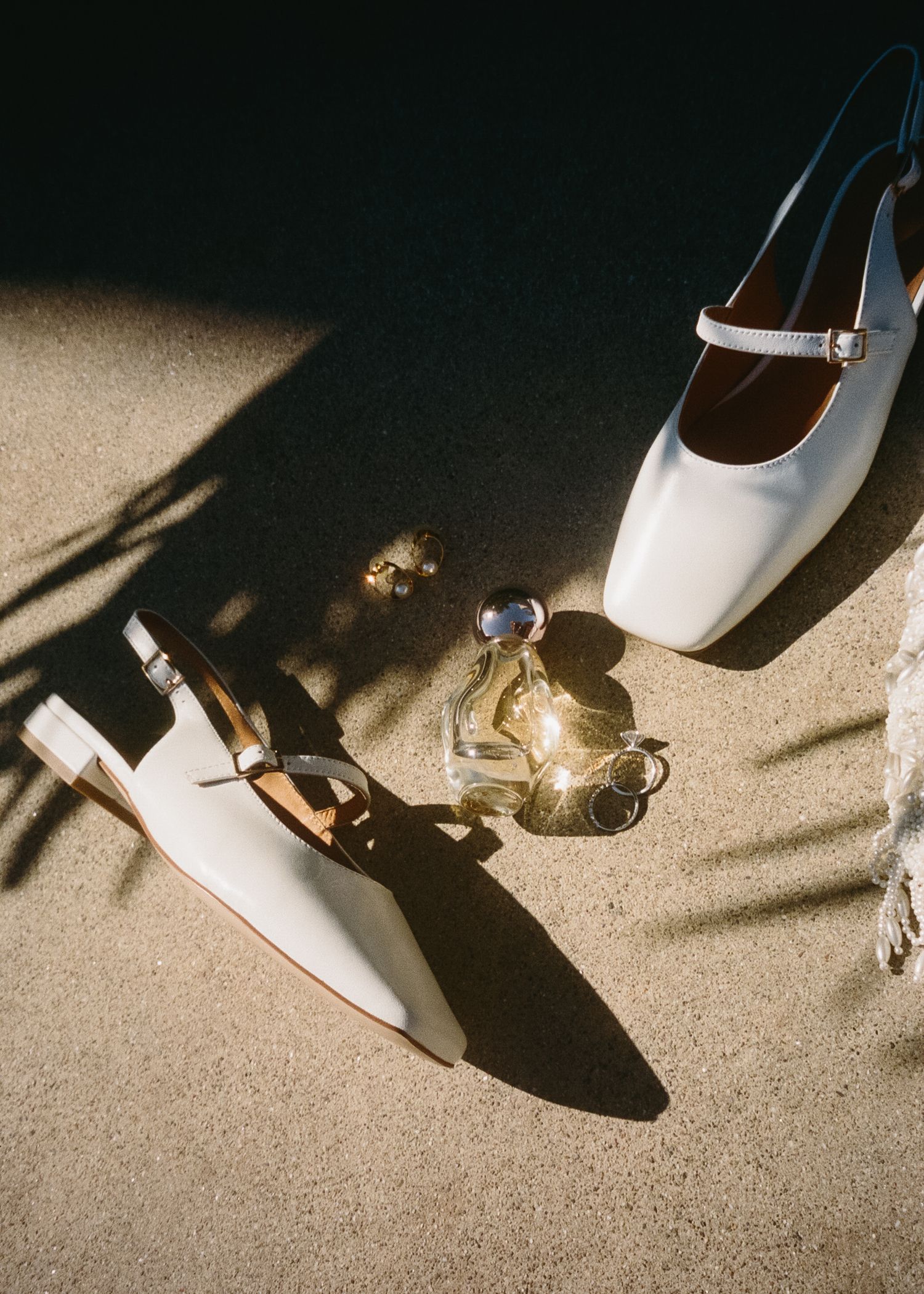 White bridal shoes casting dramatic shadows on a beige carpet.