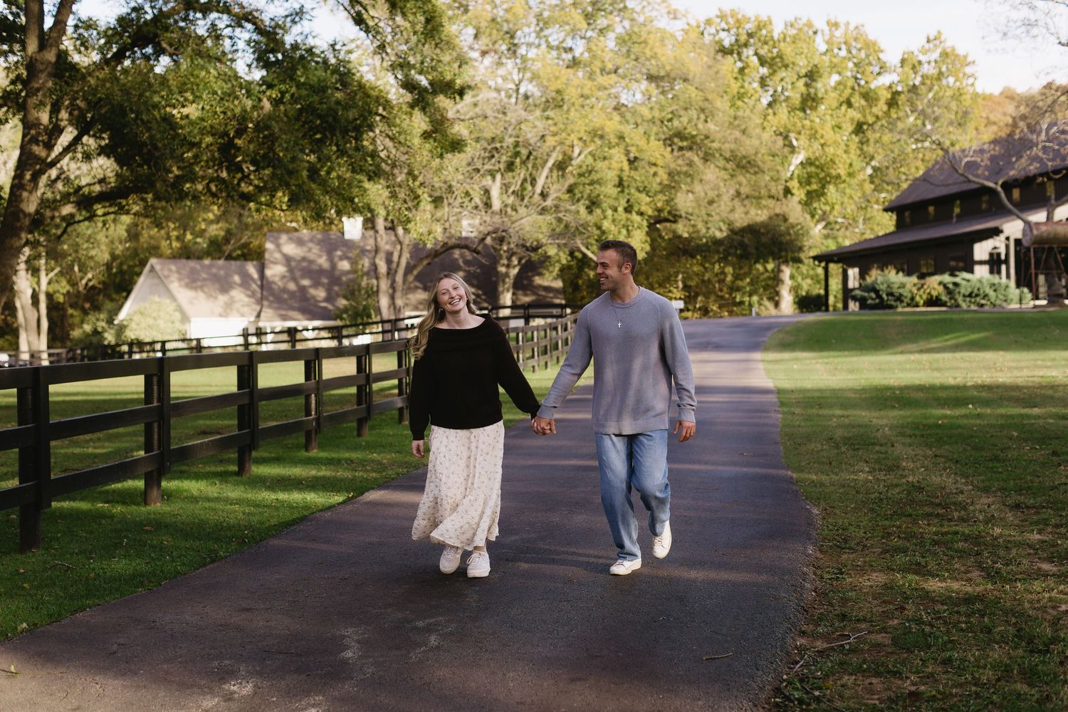 A couple walks together on a tree-lined path in a park during daytime.