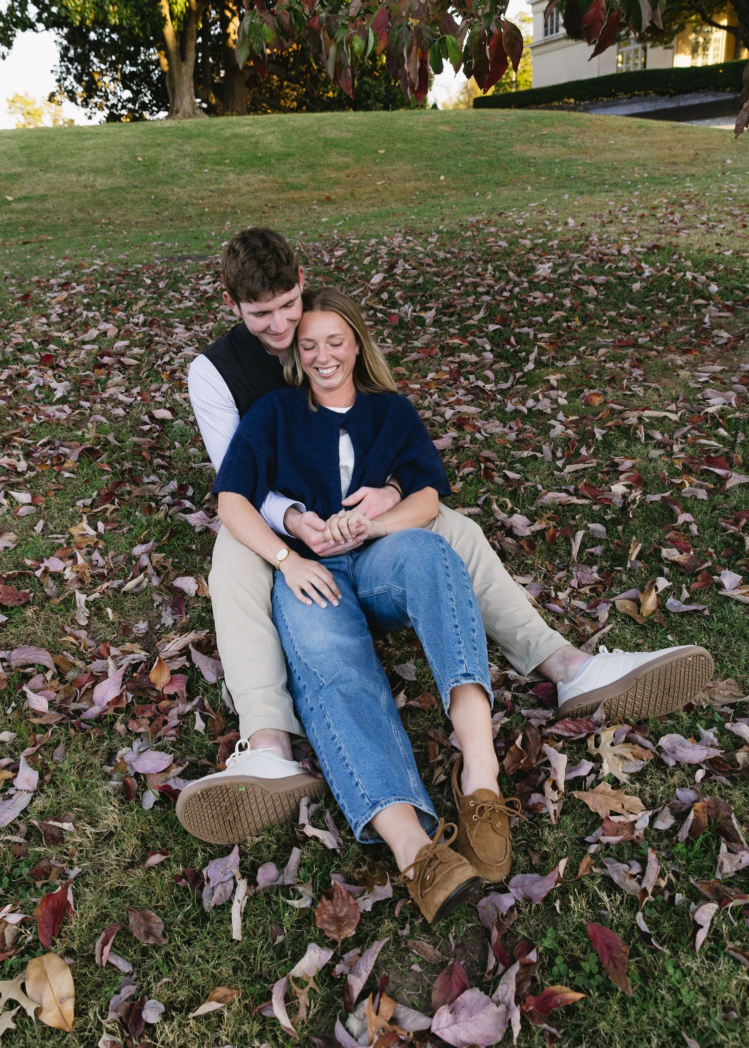 Two people playfully lounging on fallen autumn leaves.