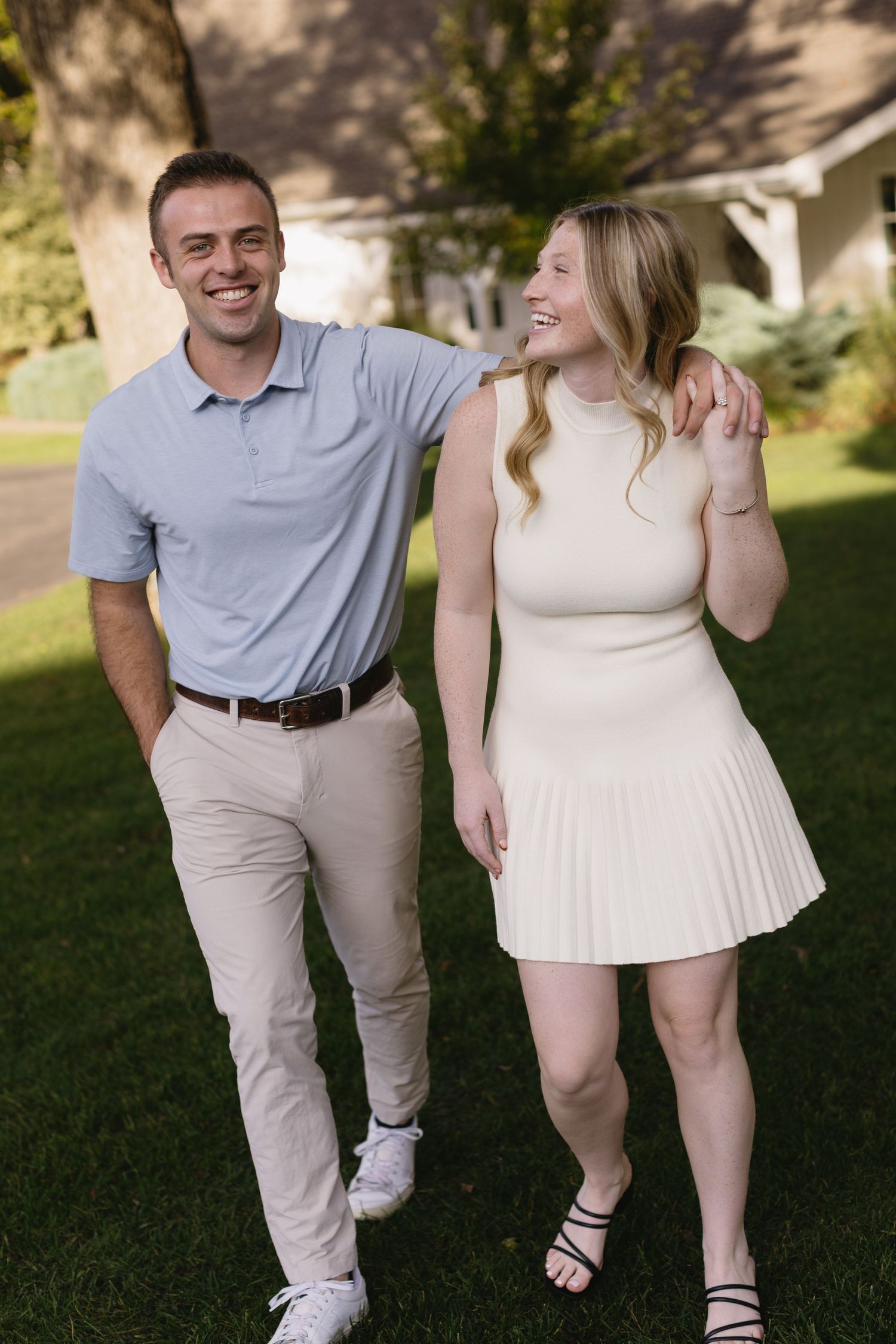 A couple walking together outdoors wearing coordinated cream and light blue outfits.