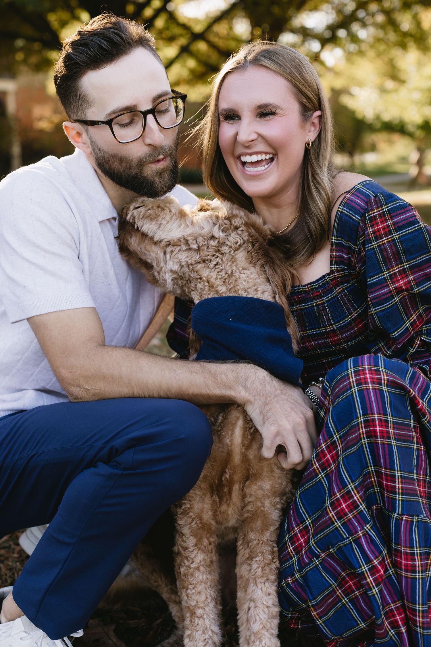 A couple and their goldendoodle dog share intimate moments during a fall photoshoot.