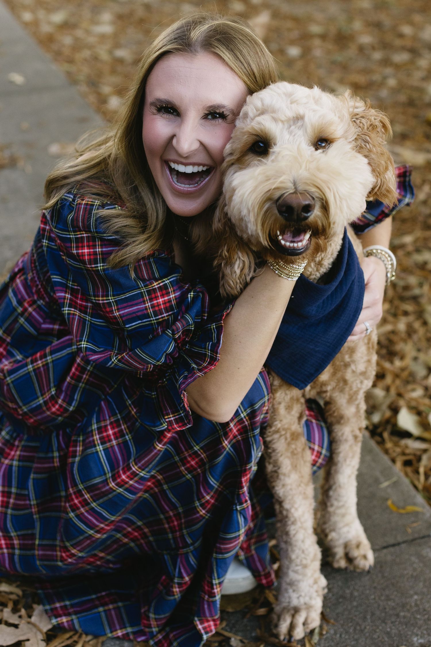 A happy goldendoodle and owner share joyful moments during an outdoor photo session.